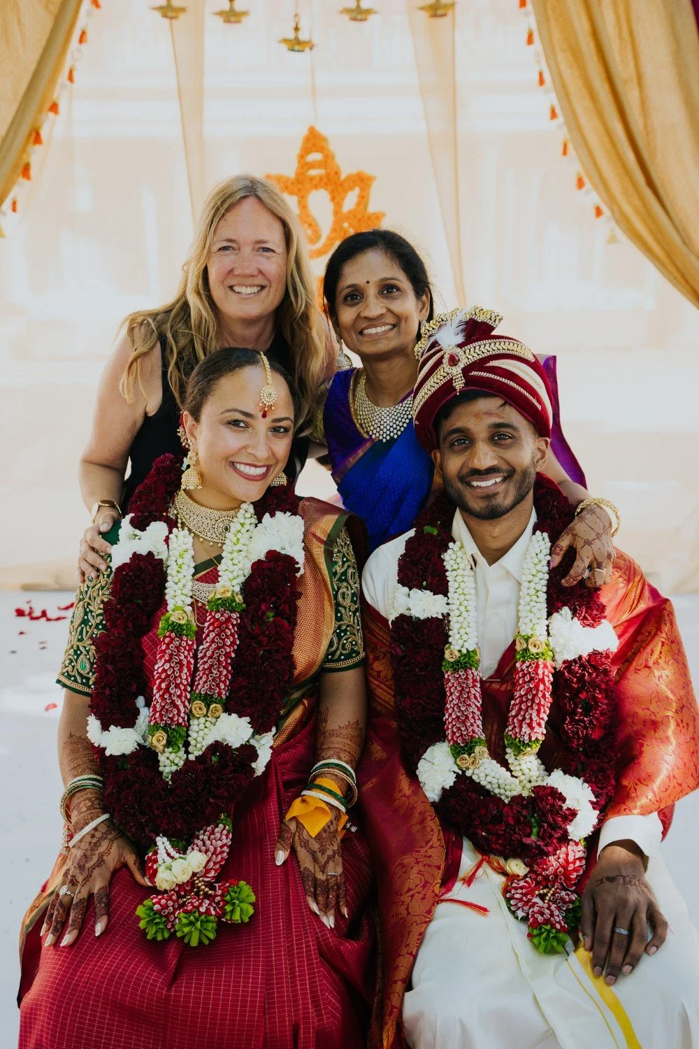 Newlyweds posing with their wedding planner and a family member after their Indian wedding ceremony.