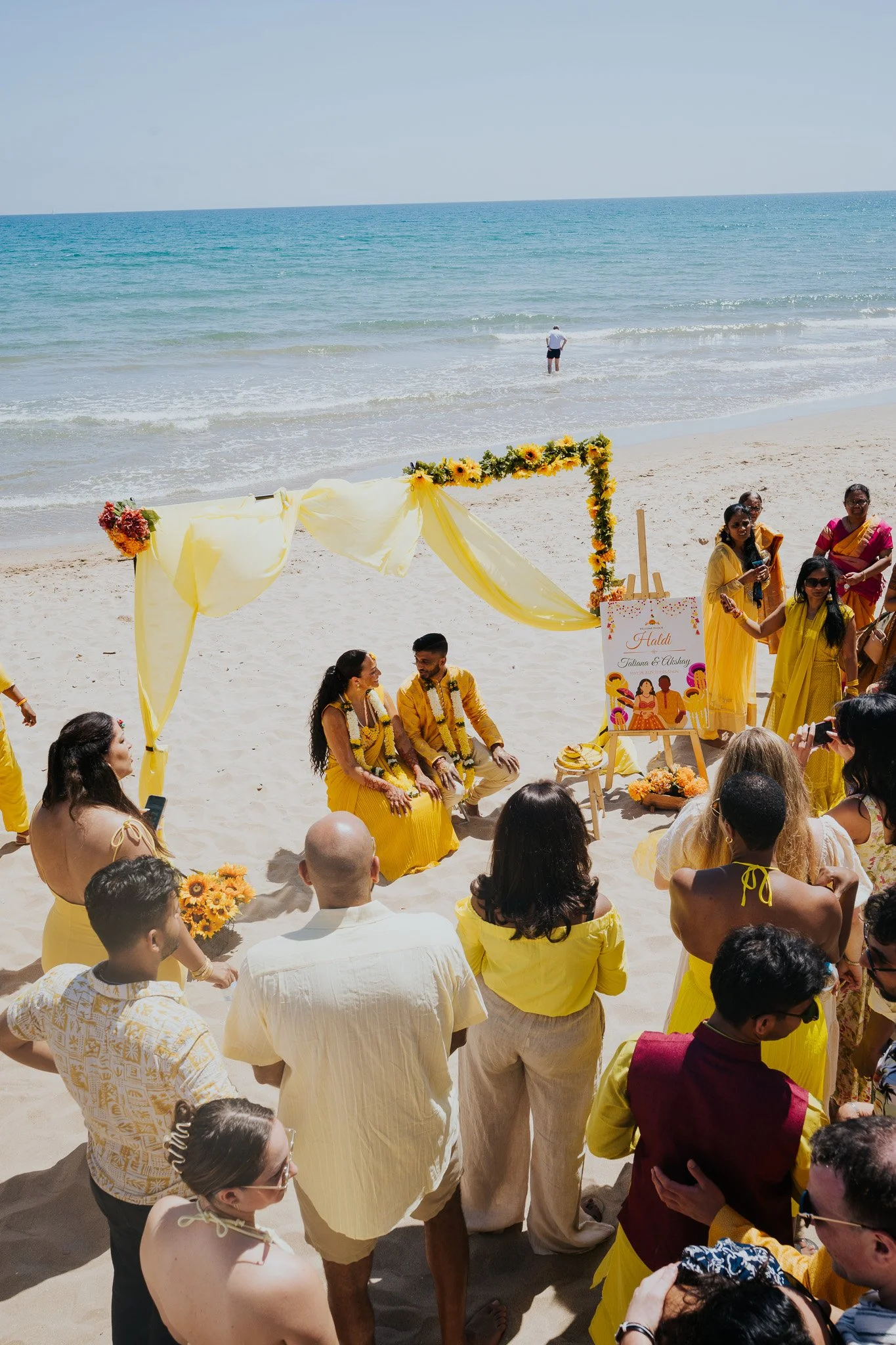 Couple celebrating a colourful Haldi ceremony on the beach in Sitges.