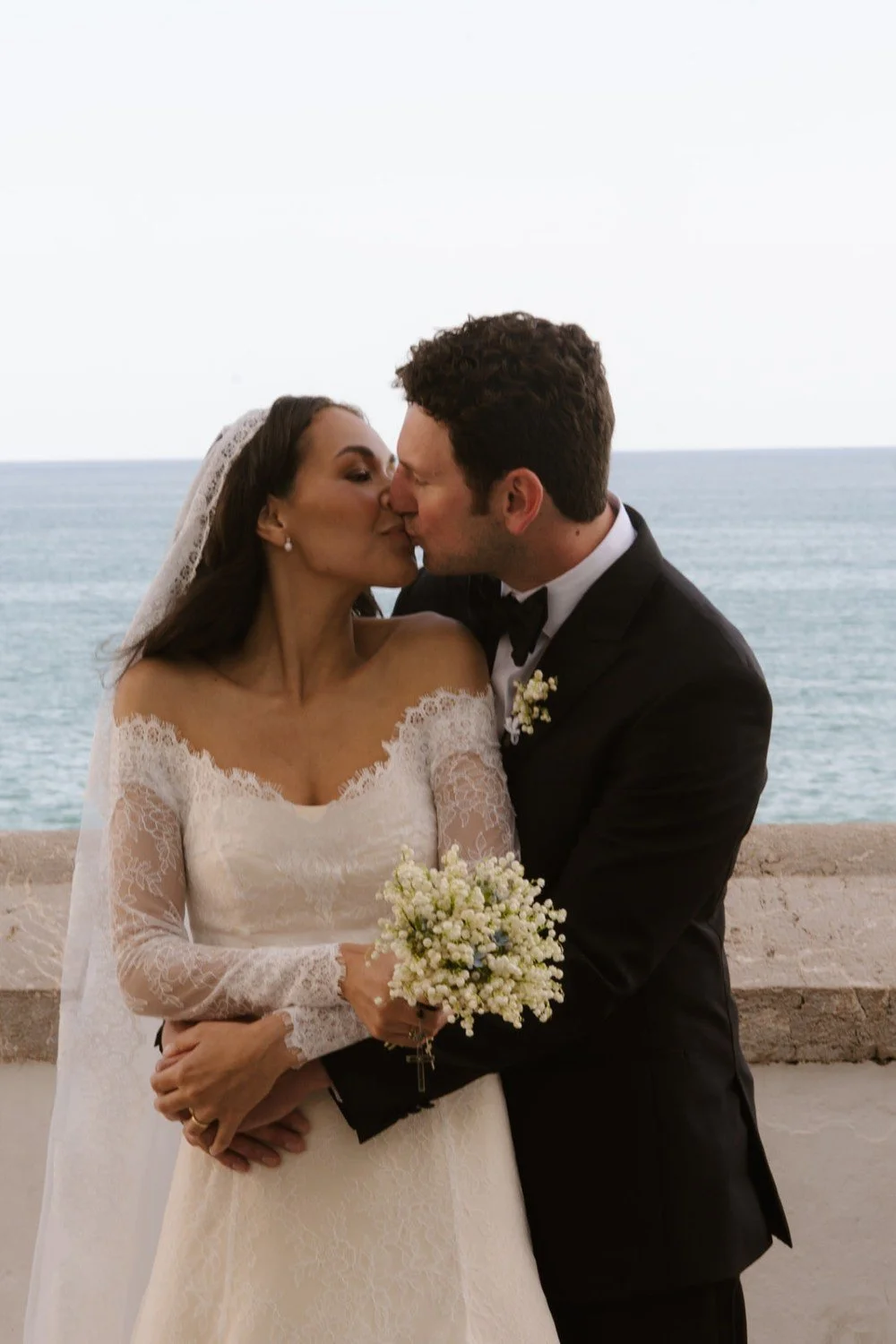 Couple sharing a kiss after their wedding ceremony in Sitges with the Mediterranean Sea behind them