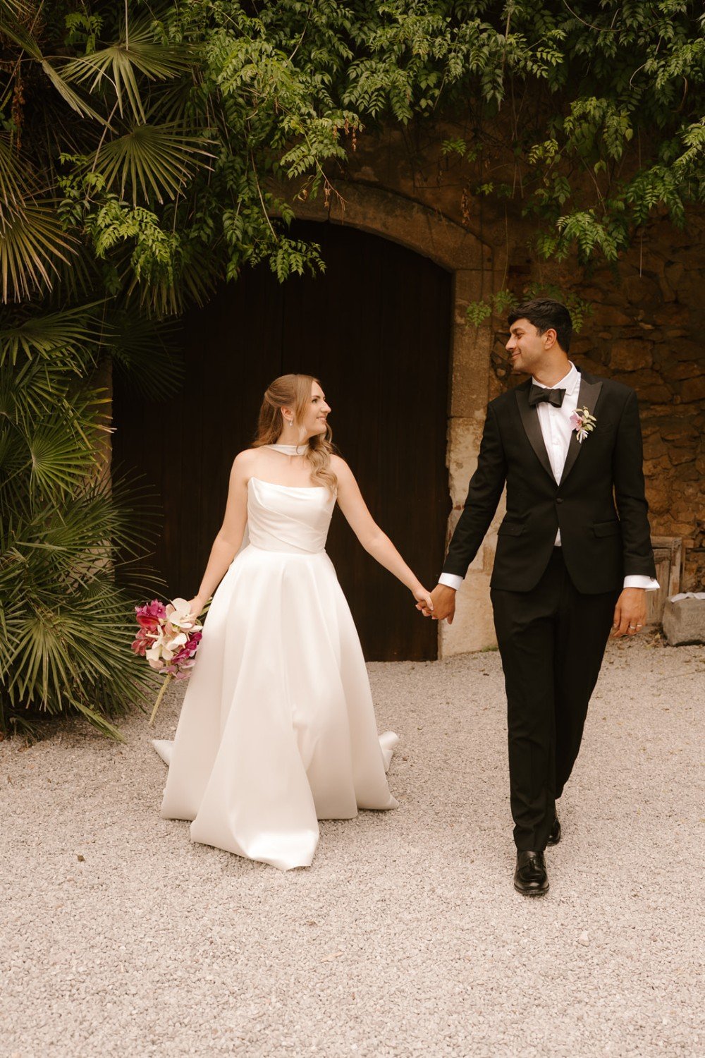 Happy newlyweds walking together in front of Casa Felix after their wedding celebration.