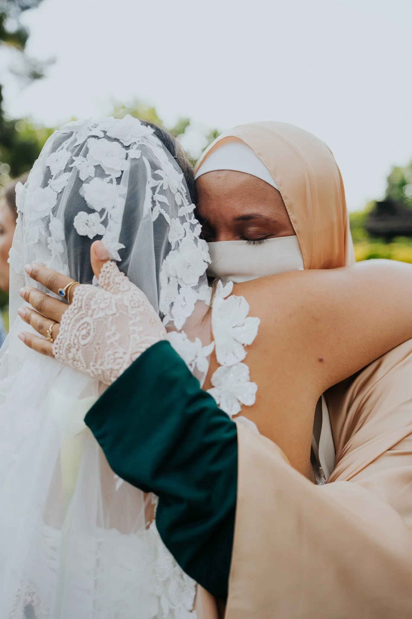 Bride embracing her Muslim friend after a wedding ceremony.