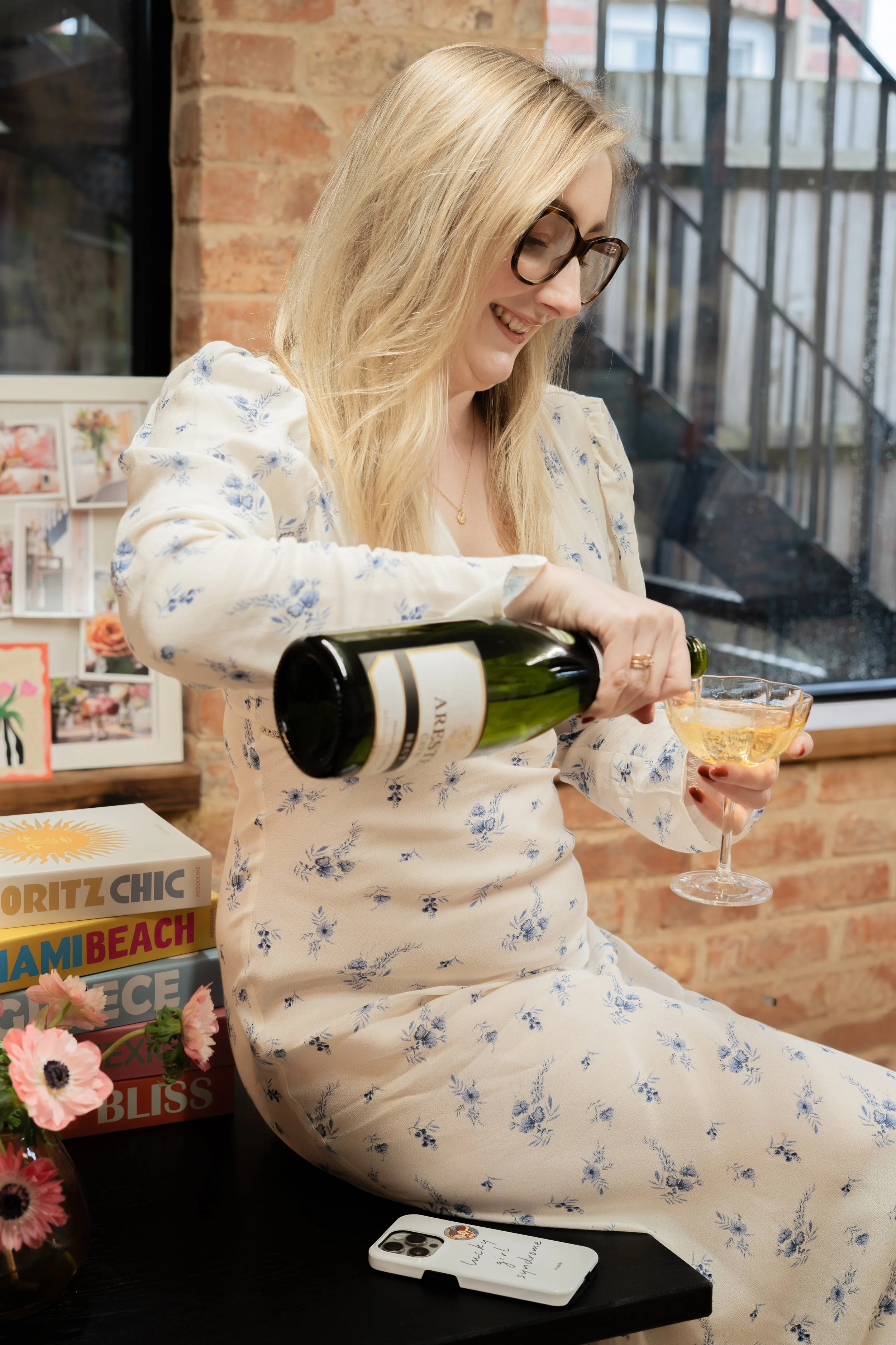 Wedding and SEO expert Zoe Burke pours champagne into a coupe glass while smiling