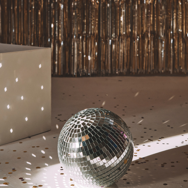 A sparkling disco ball on a confetti-strewn floor at a wedding