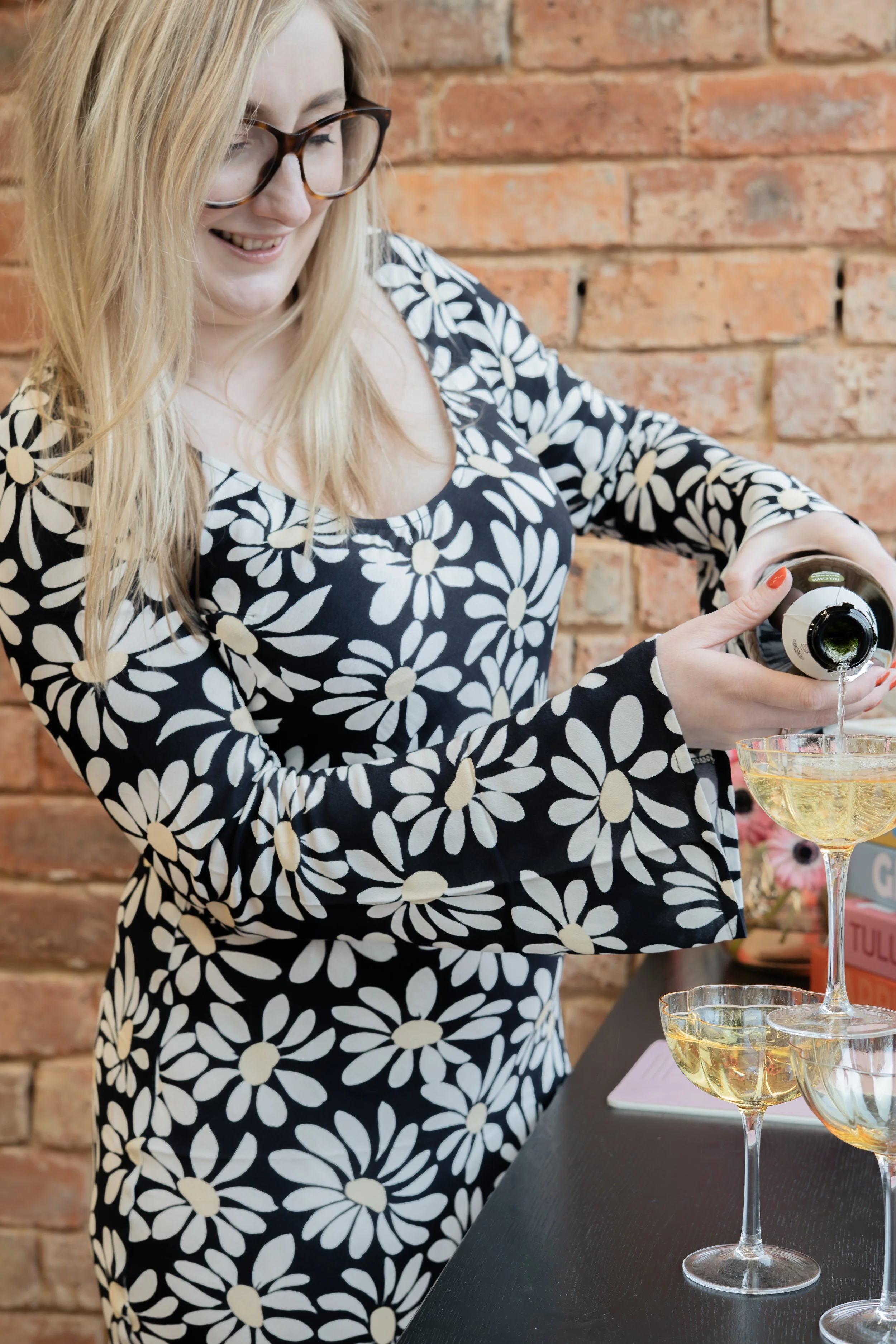 Leading SEO and wedding expert Zoe Burke smiles as she pours champagne into a coupe