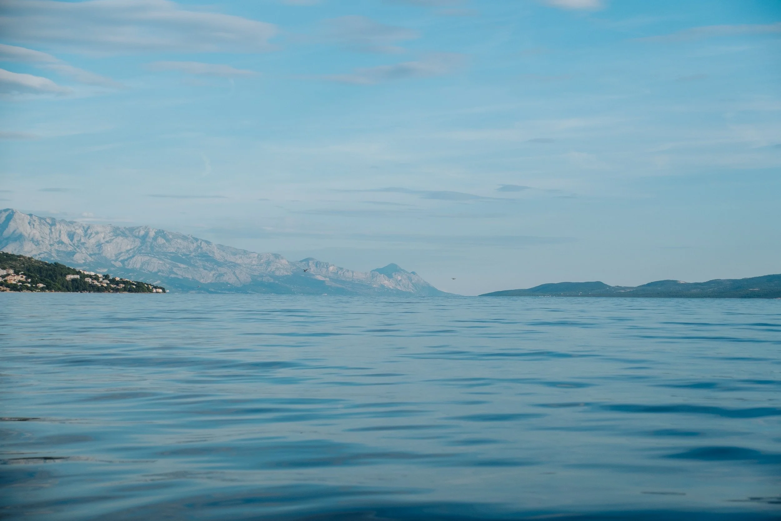 Calm blue lake with mountains in the distance and partly cloudy sky