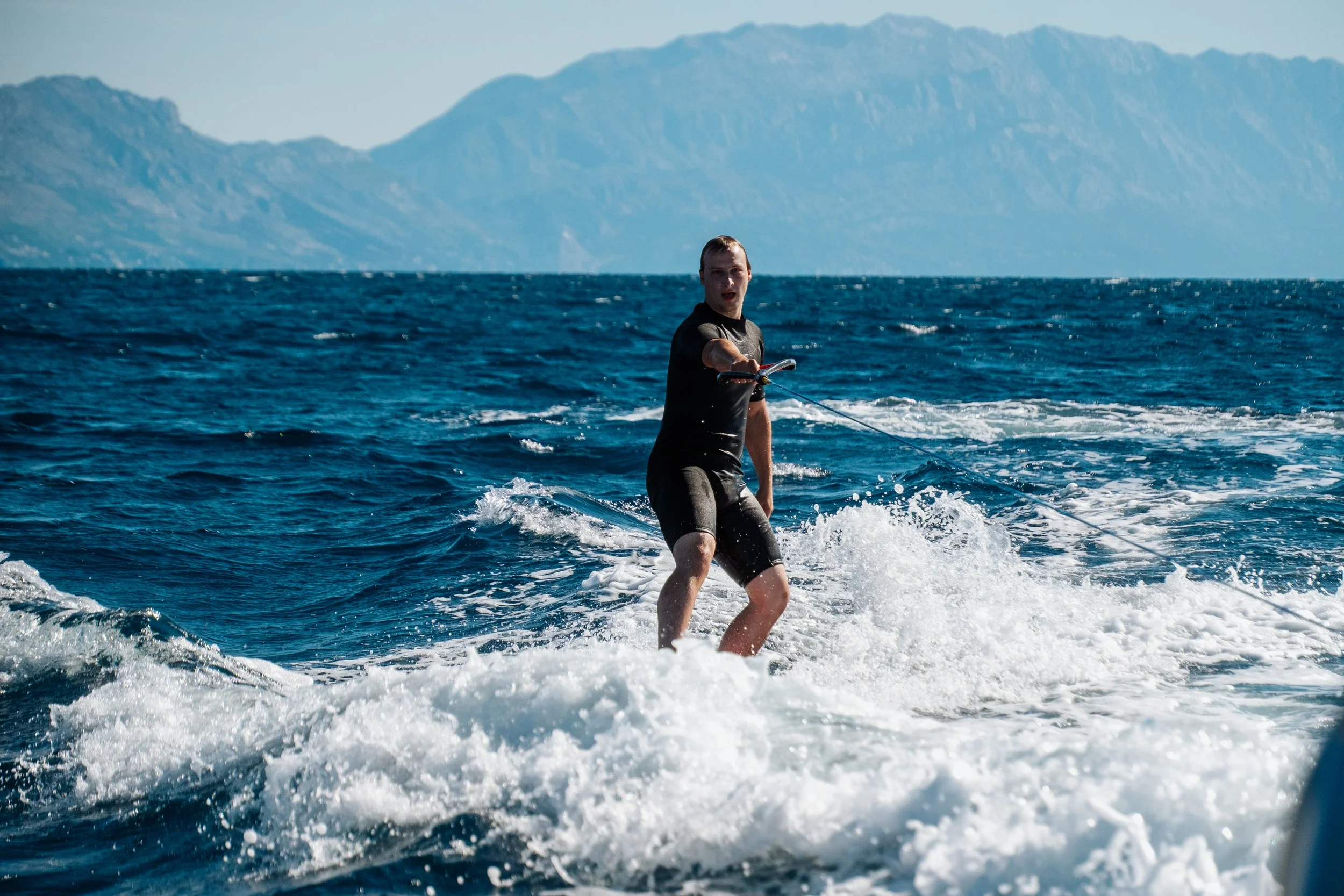 A person wakeboarding on the ocean with a mountain in the background.