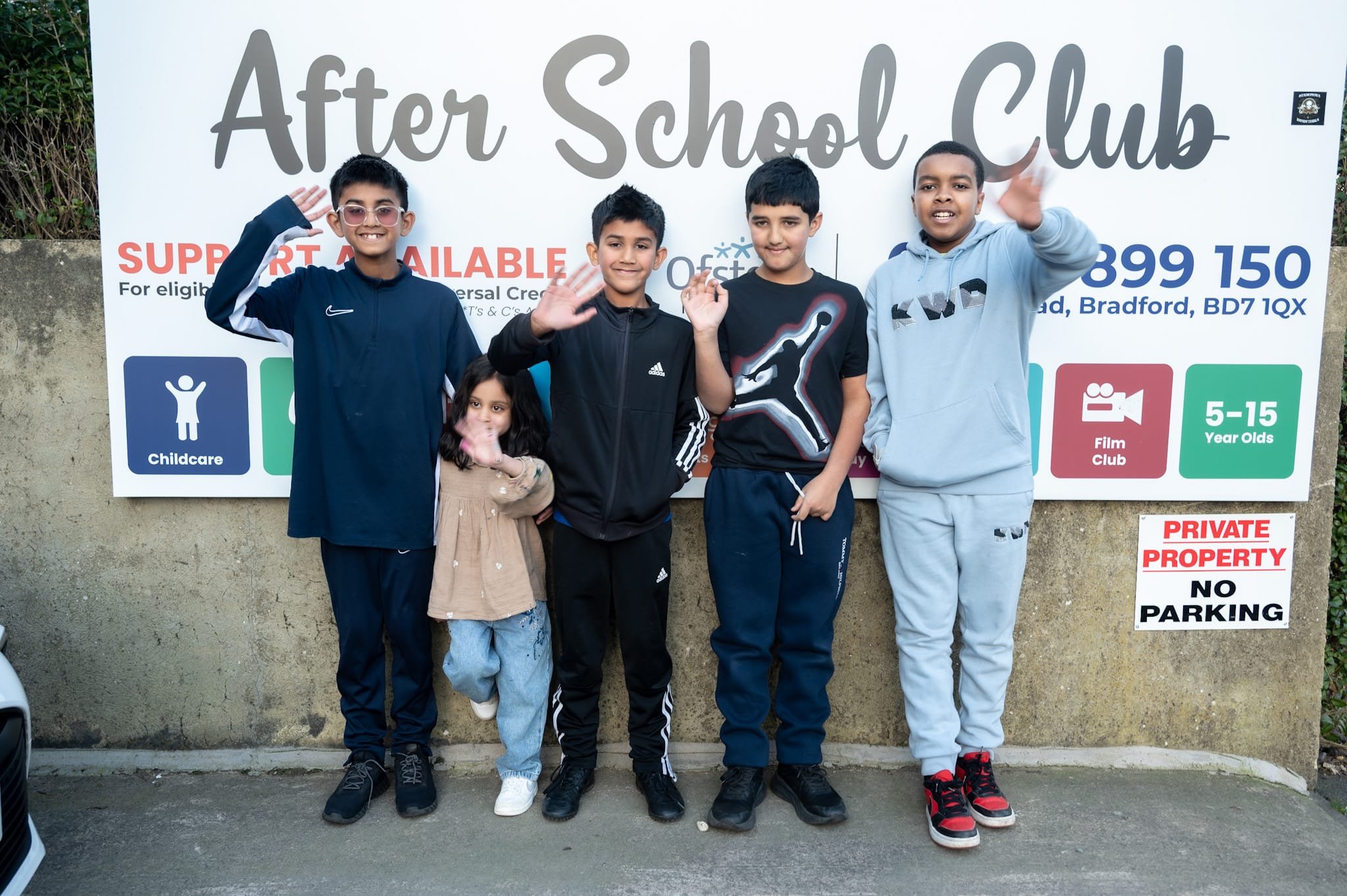 Group of kids standing in front of an 'After School Club' sign.
