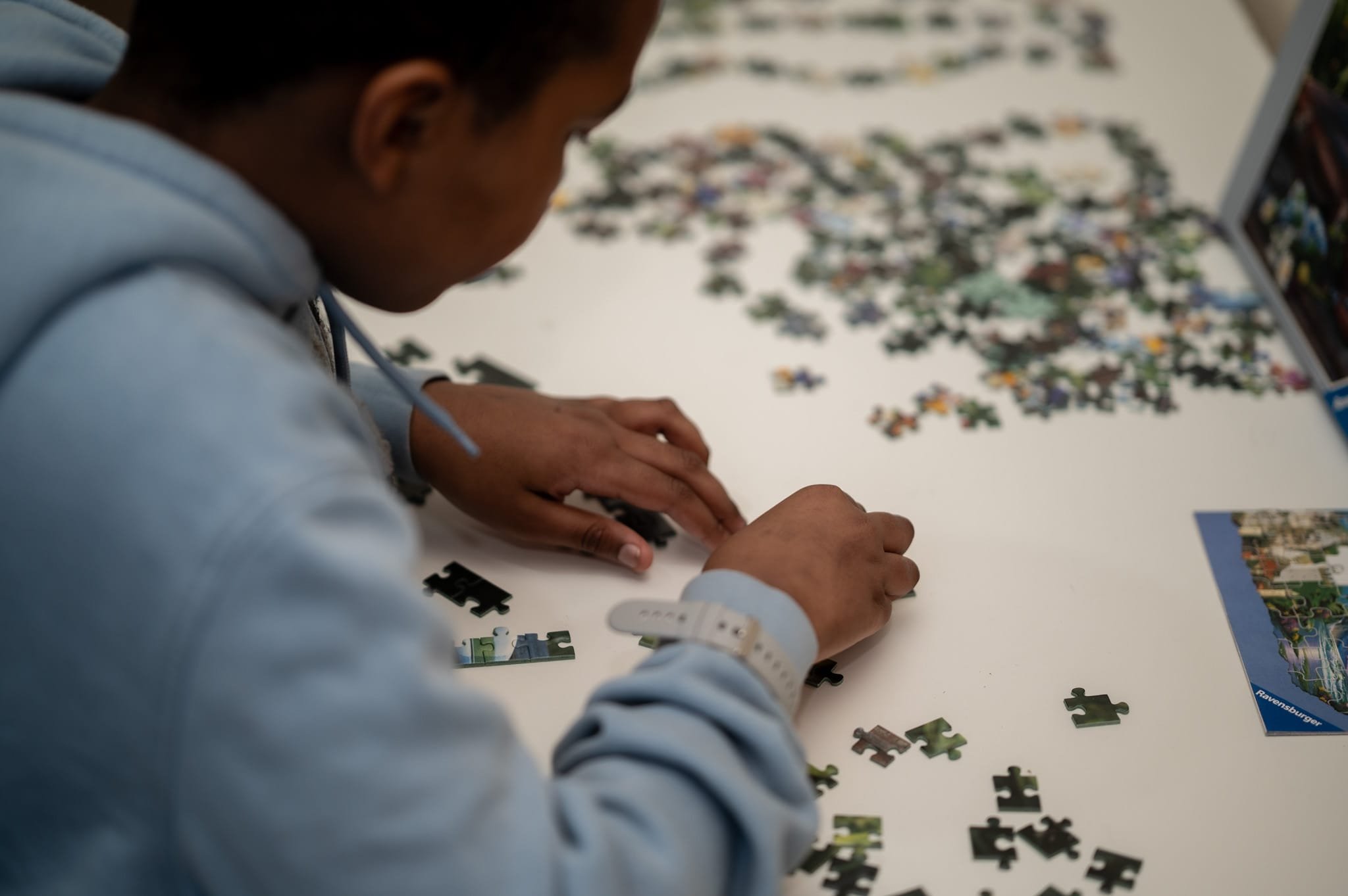Person assembling a jigsaw puzzle on a table