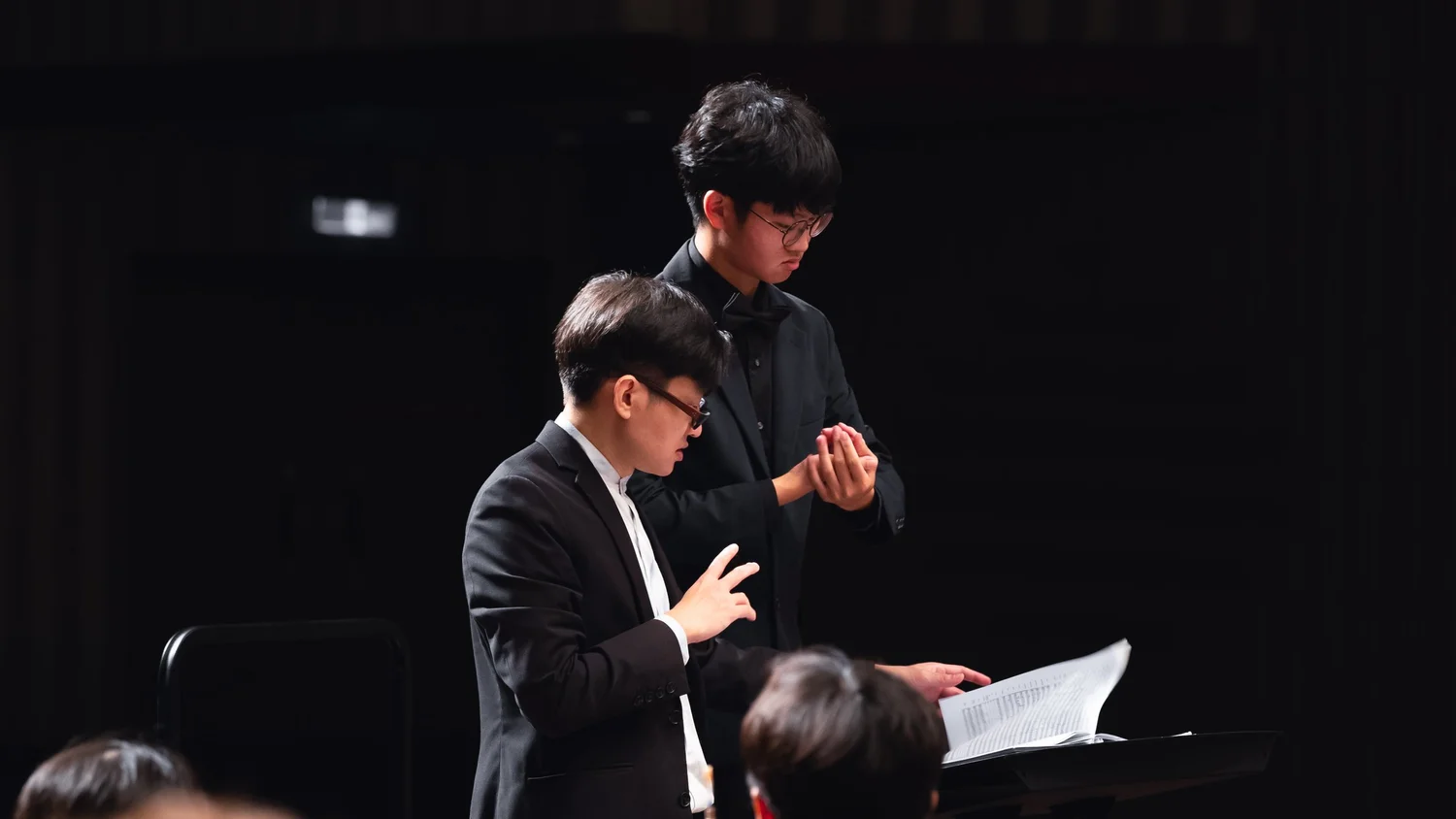 青年指揮於舞台上帶領樂團演出