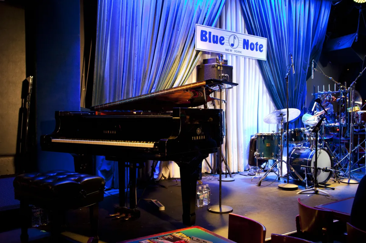 Stage setup at Blue Note New York with a Yamaha grand piano and drum set.