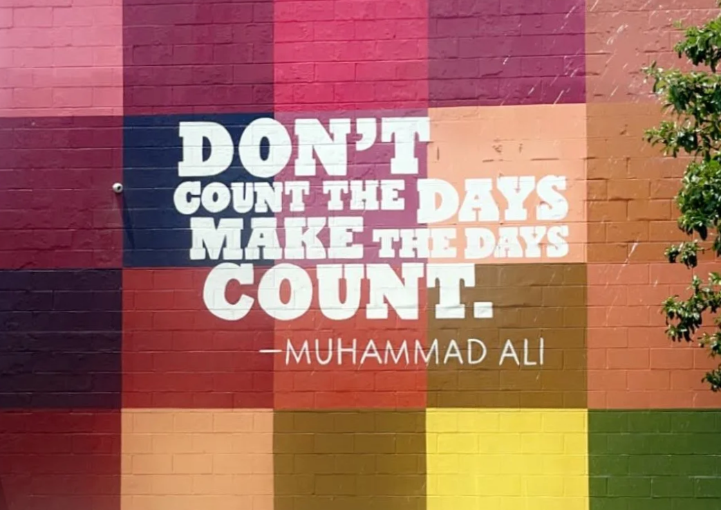 Colorful mural with a quote by Muhammad Ali that reads, "Don't count the days, make the days count."
