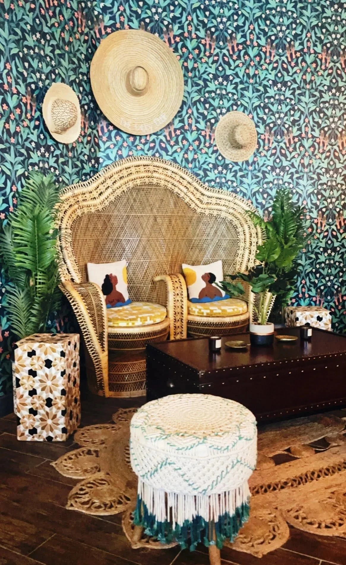 Boho-style living room with wicker chairs, decorative wall hangings, plants, and textured rugs.