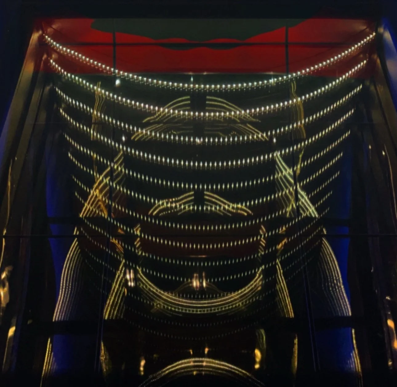 Reflection of ceiling lights on a glass surface creating a symmetrical pattern.