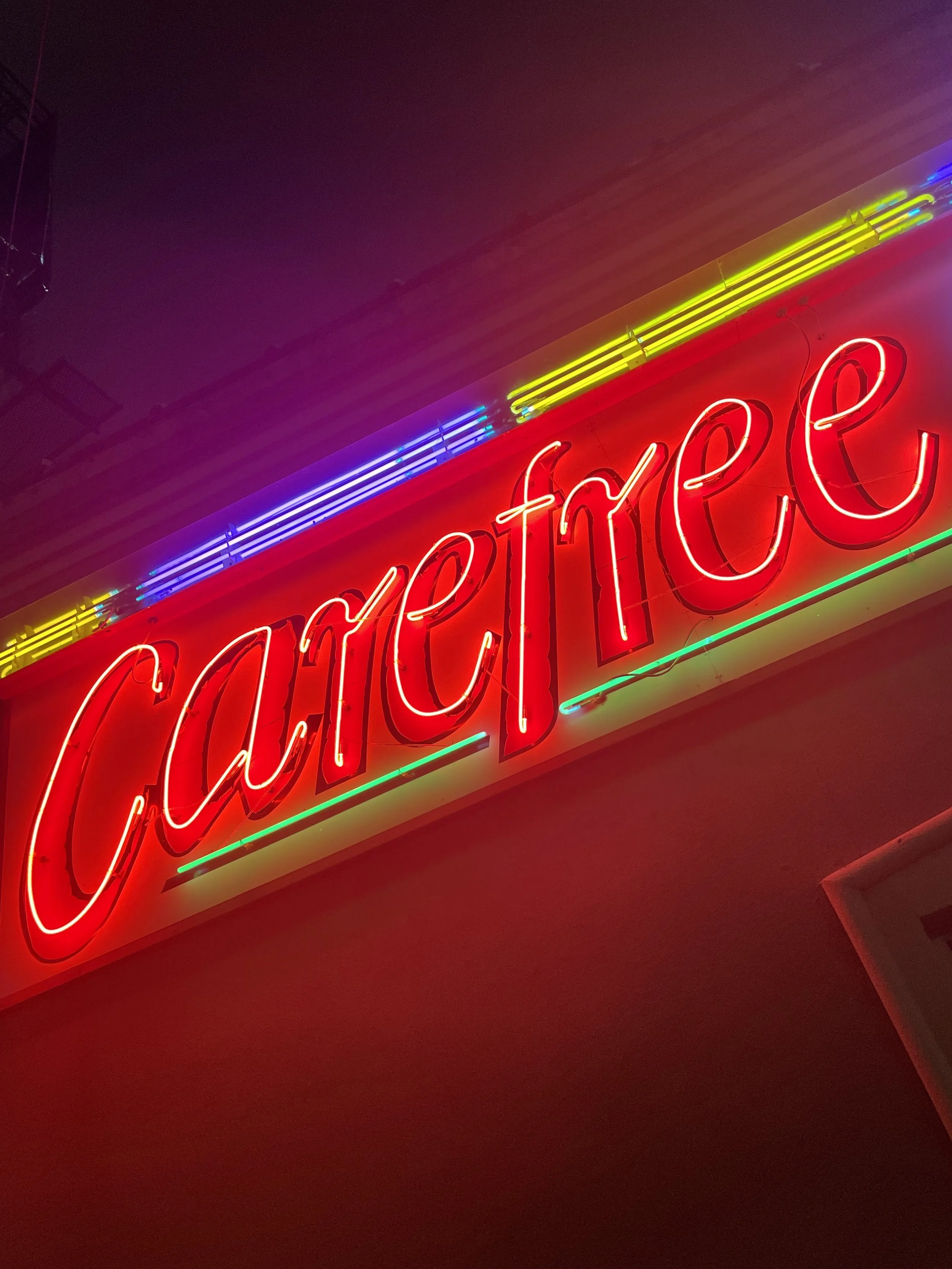 Neon sign reading 'Cafeteria' illuminated in red with yellow, blue, and green accents.