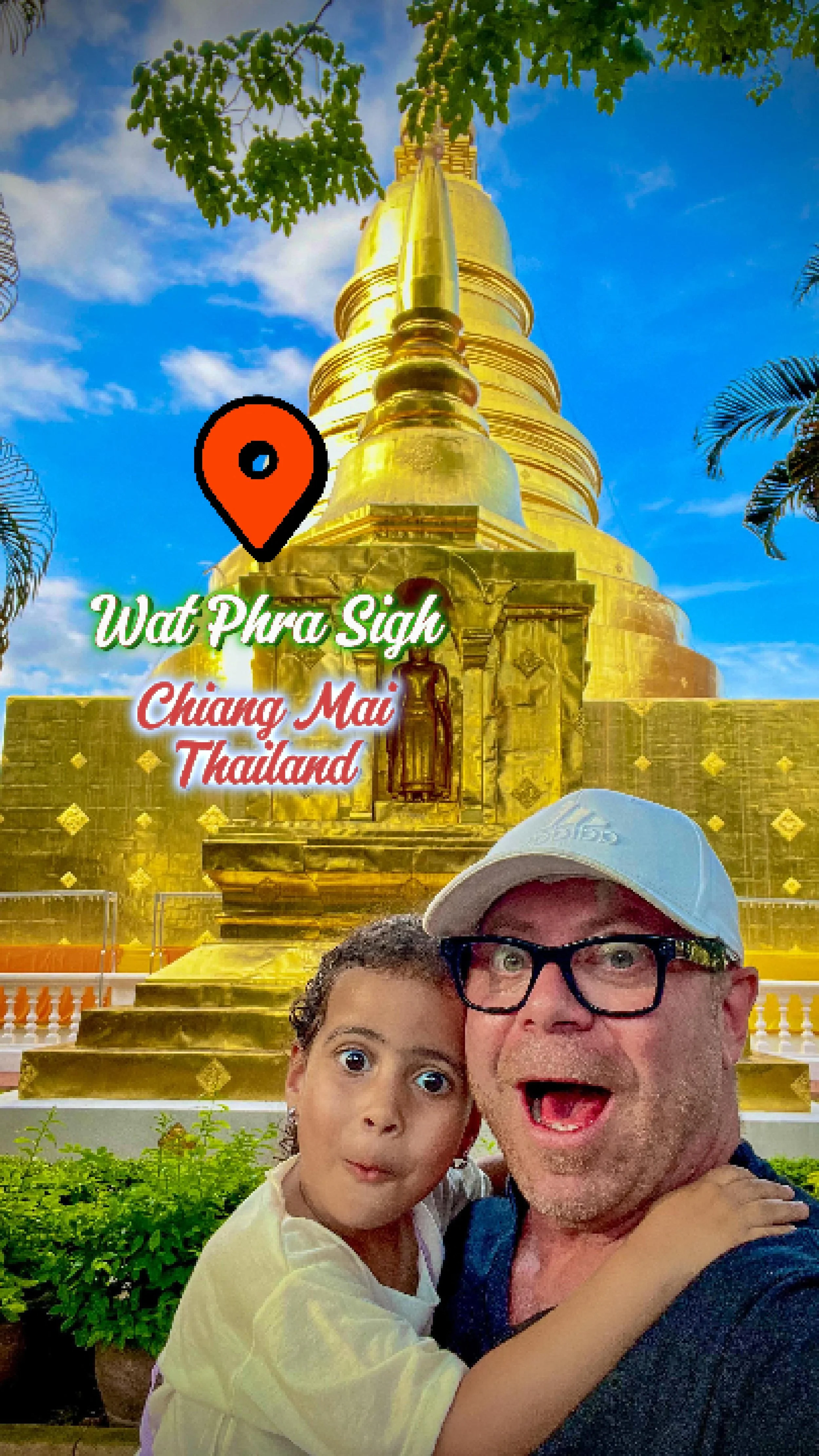 Una coppia di persone sorridenti in primo piano davanti a un monumento dorato a Wat Phra Singh a Chiang Mai, Thailandia, con un cielo blu e alcune piante verdi.
