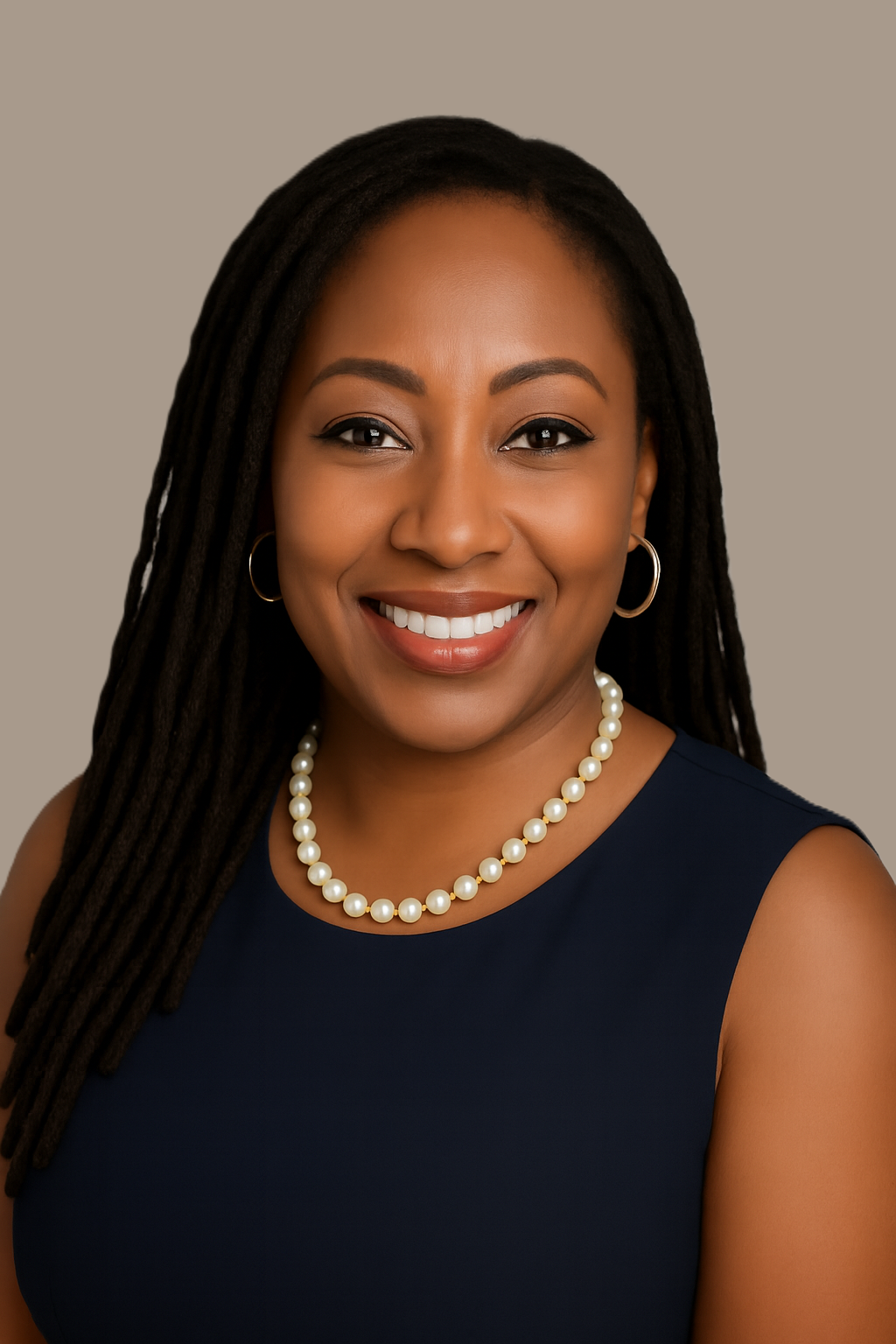 A professional woman with long dreadlocks, wearing a navy sleeveless top, pearl necklace, and hoop earrings, smiling against a plain background.