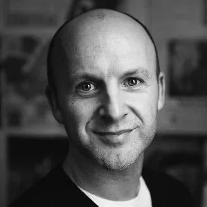 Black and white portrait of a bald man smiling at the camera