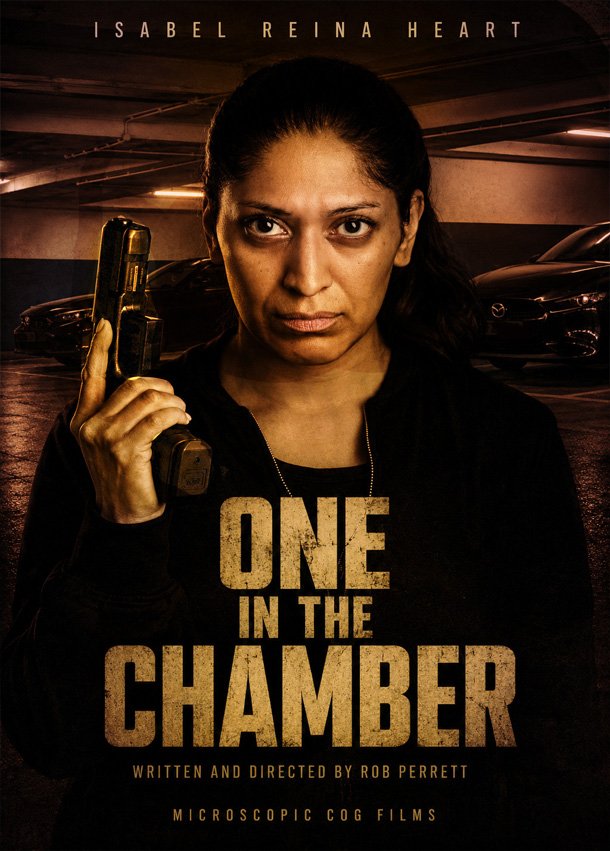 The background shows parked cars and concrete pillars. The woman appears serious and determined. Text at the top reads 'ISABEL REINA HEART,' and the title 'ONE IN THE CHAMBER' is prominently displayed in large letters in the center. Additional text at the bottom includes 'WRITTEN AND DIRECTED BY ROB PERRETT' and 'MICROSCOPIC COG FILMS.'
