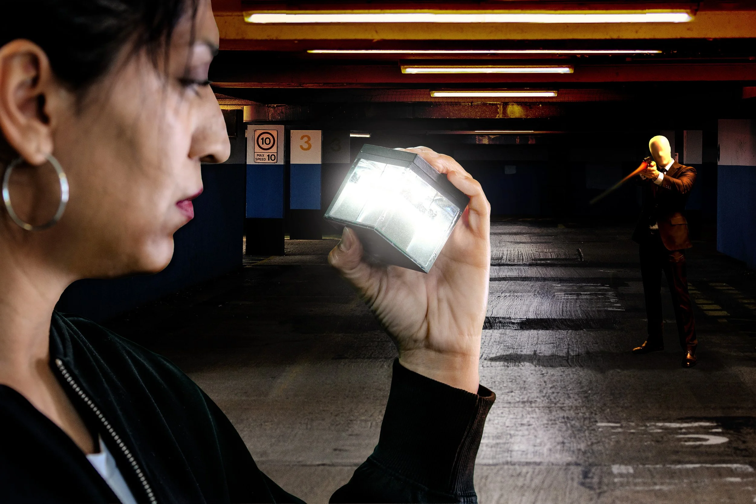 Isabel Rainer Heart in the foreground appears to be using a mirror or reflective device, with her face in profile on the left side of the image. In the background, a bald, faceless figure dressed in black is pointing a gun at her in a parking garage.