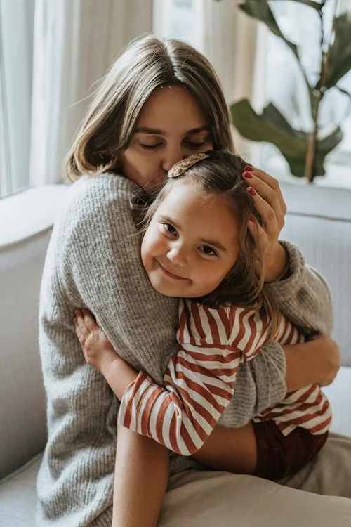 L'image représente une maman tenant son jeune enfant dans les bras, à qui elle voudrait faire écrire une lettre d’amour en cadeau d’anniversaire