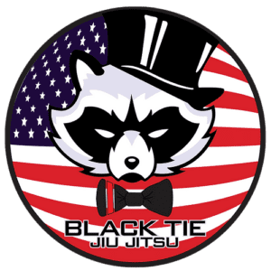 A circular logo featuring a raccoon wearing a top hat and bow tie, with an American flag background and the text 'Black Tie Jiu Jitsu' at the bottom.