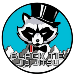 A raccoon mascot wearing a black top hat and bow tie, with mountains in the background and the text 'Black Tie Jiu Jitsu' at the bottom.
