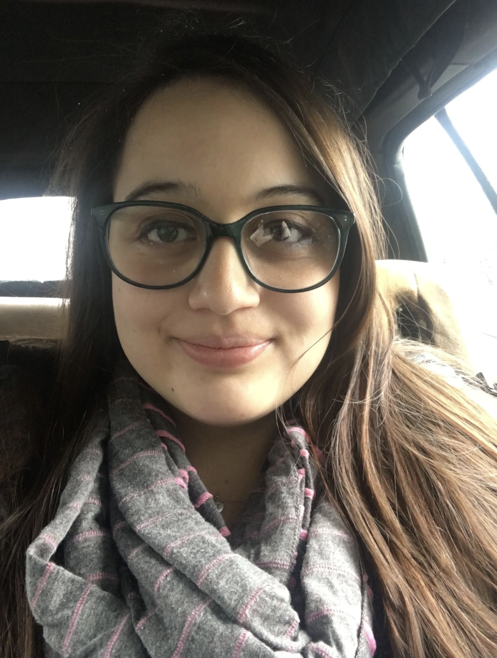 Person wearing glasses and a patterned scarf in a car.