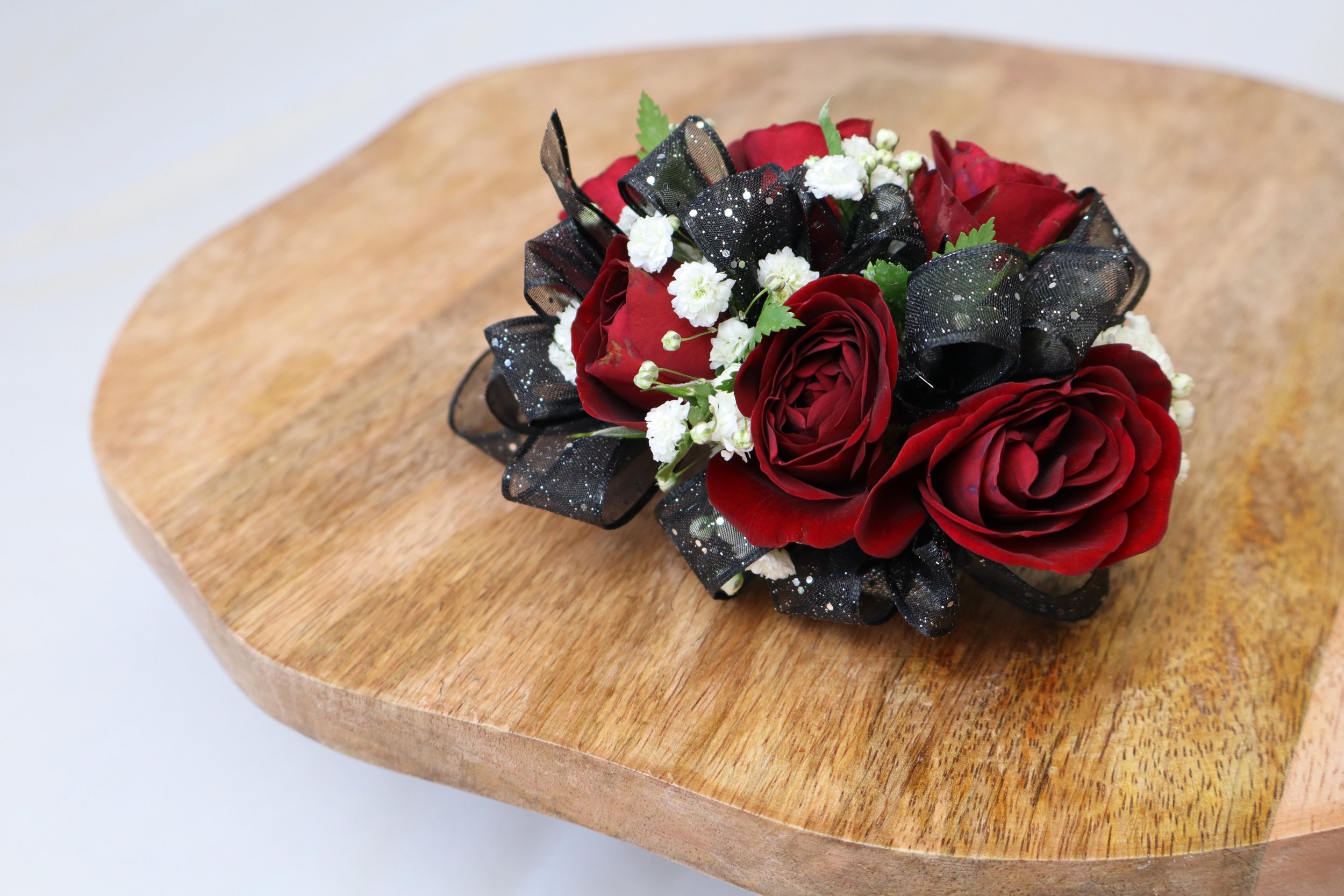 Red rose corsage with black ribbon for prom or formal event