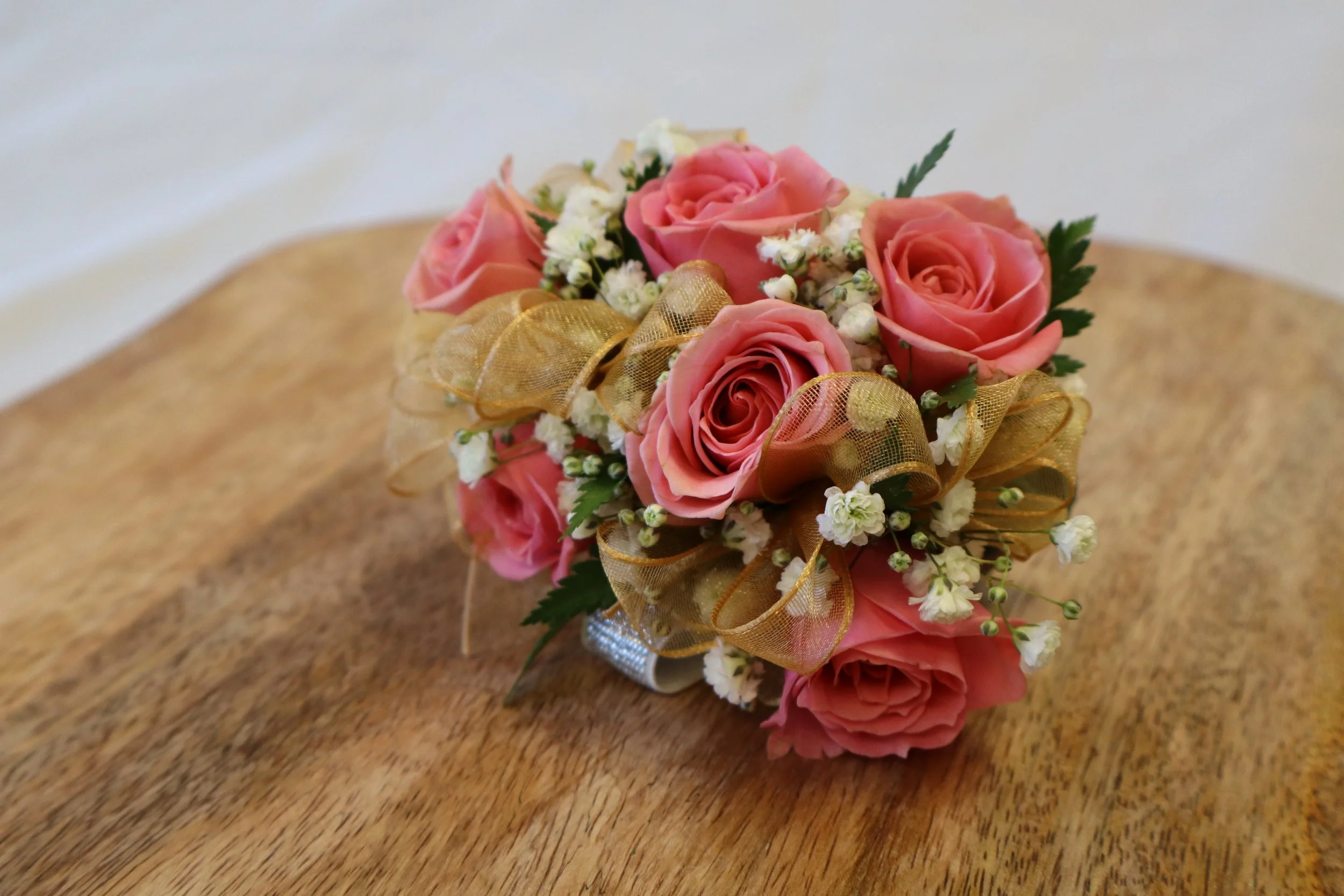Prom rose corsage with coral spray roses and gold ribbon in Sacramento