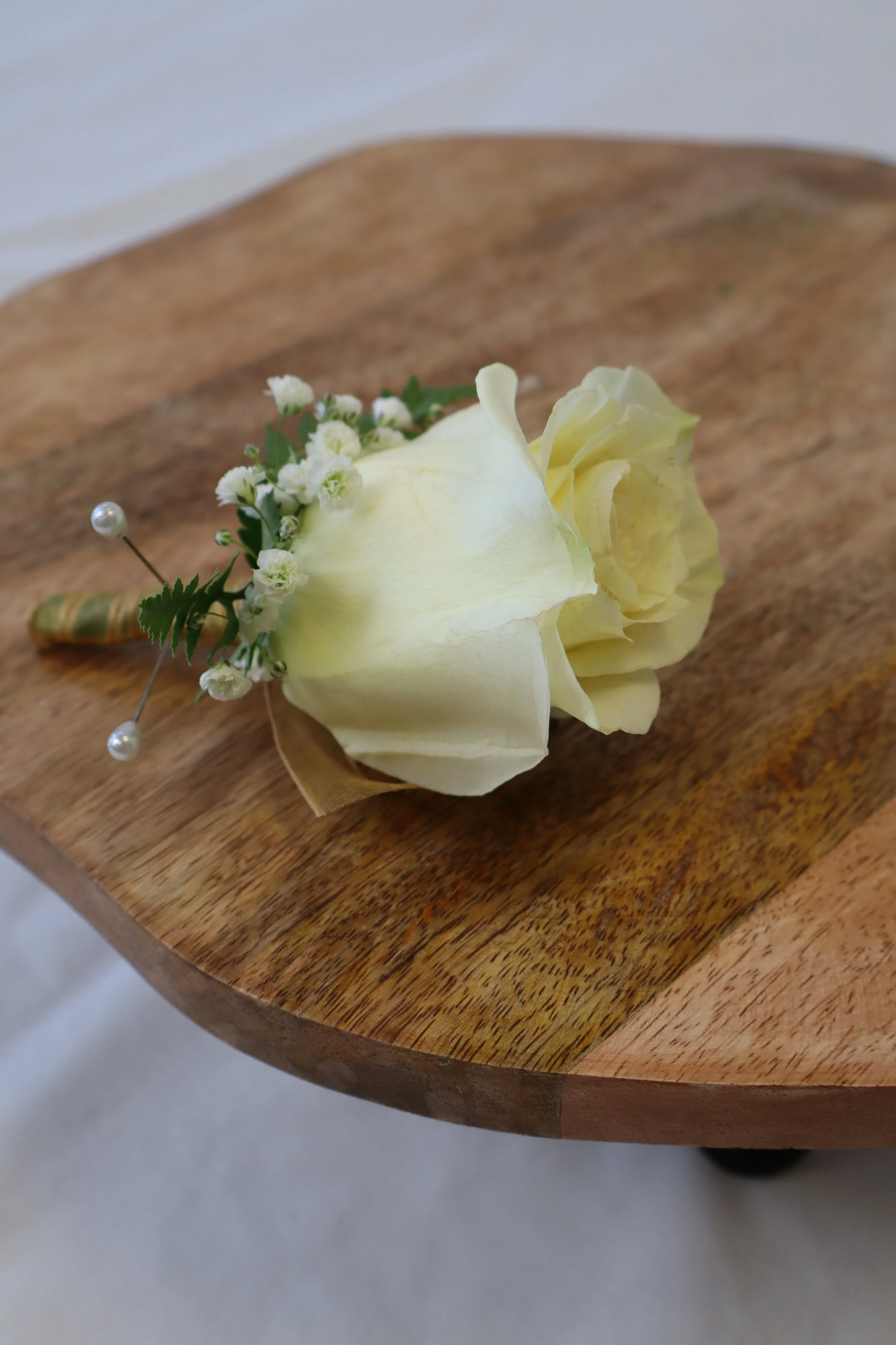 Rose boutonniere with greenery and ribbon wrap for prom or formal event