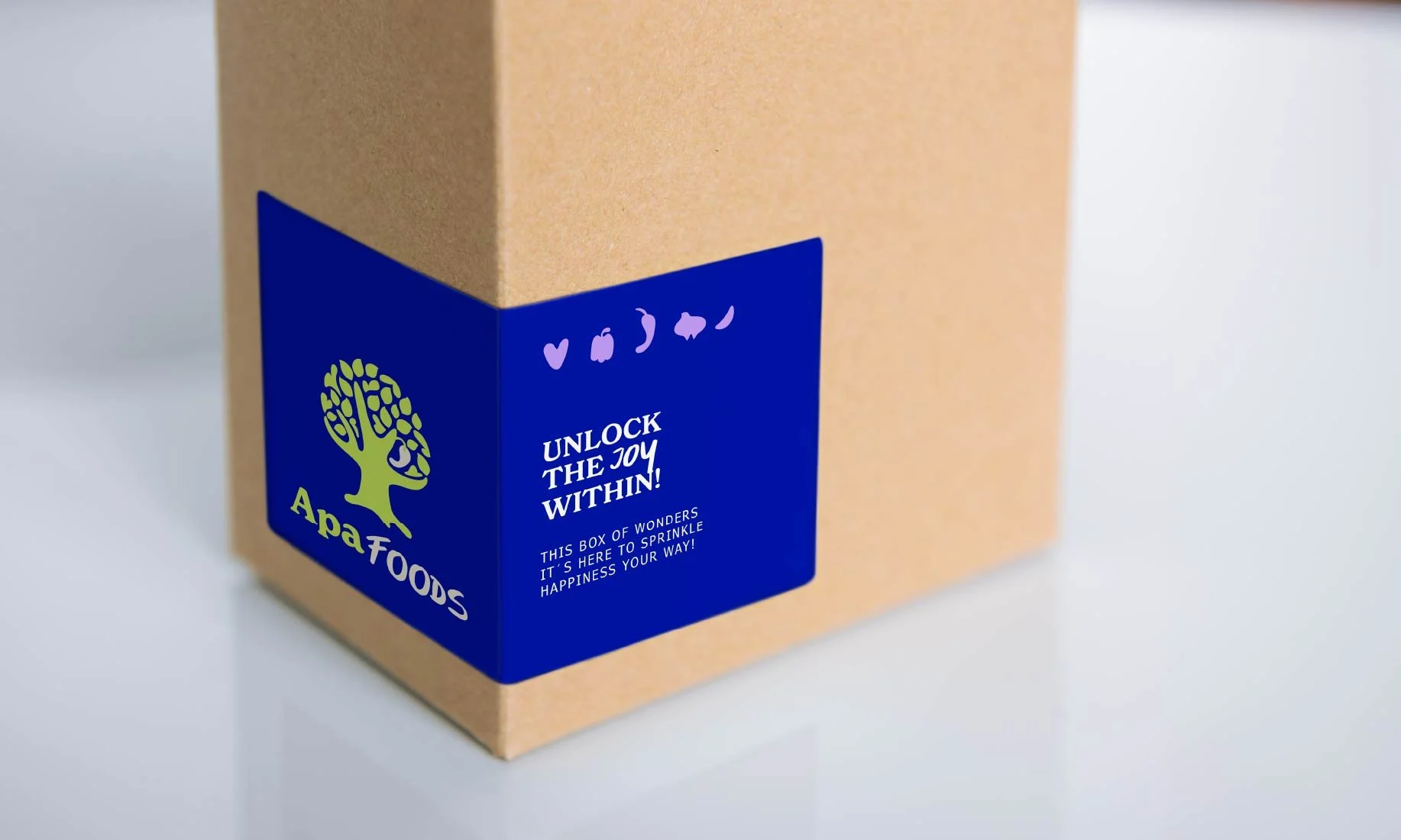 Caja de productos con una etiqueta azul que dice 'Apafoods', con un árbol verde y texto que dice 'Unlock the joy within!'.