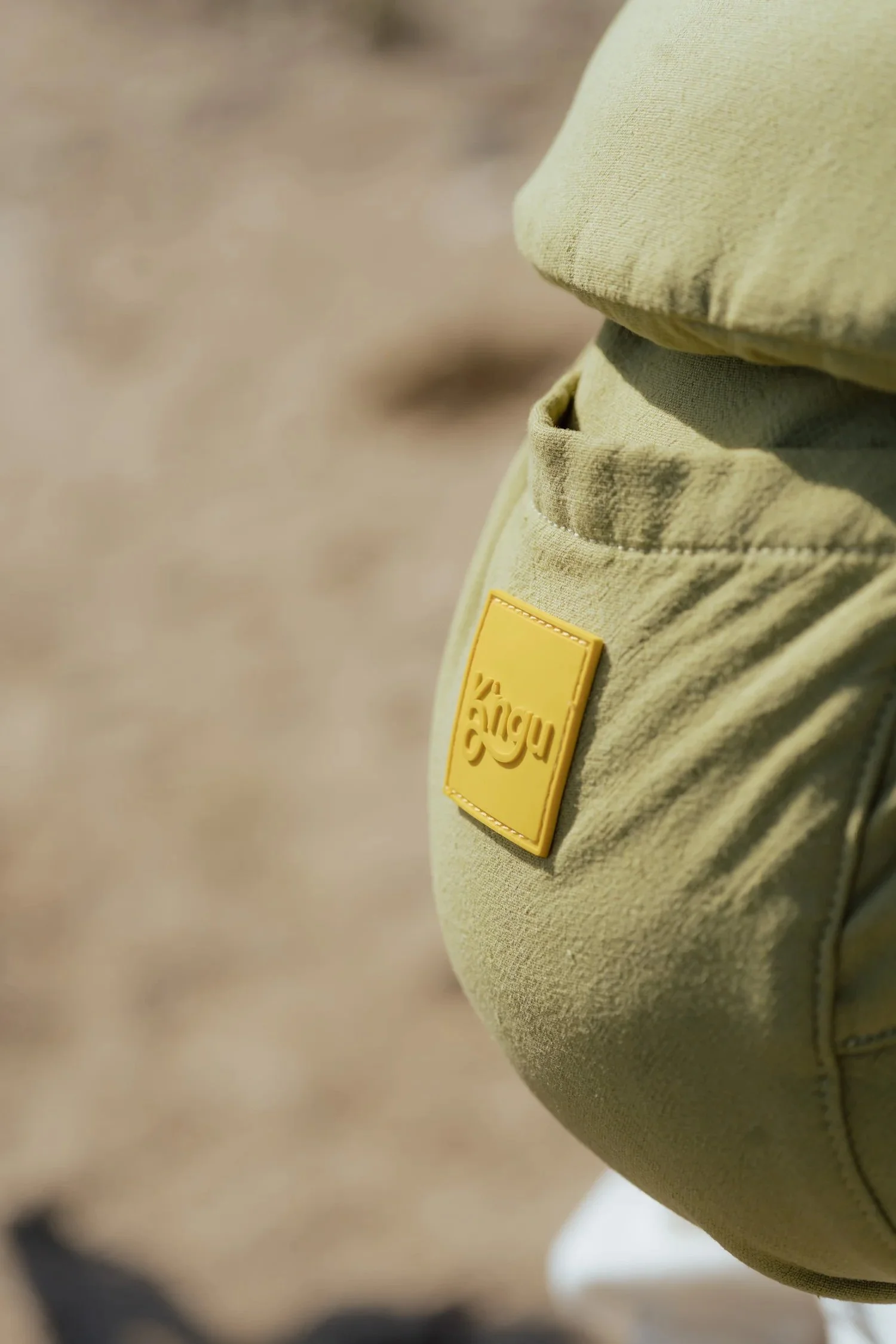 Un bolsillo de pantalón en color verde con una etiqueta amarilla que tiene la palabra 'vigu' en relieve.