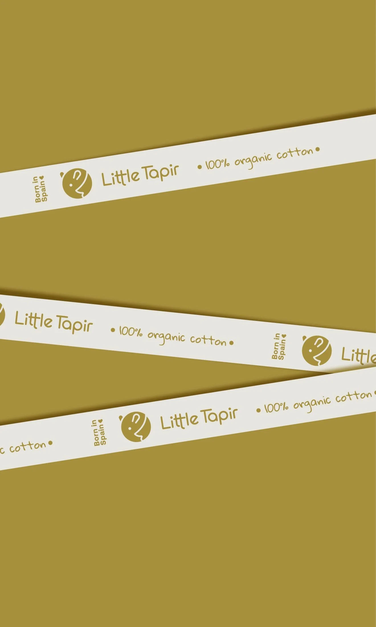 Etiquetas de cinta de algodón orgánico para bebés de la marca Little Tapir, de color dorado y blanco, que indican que es 100% algodón orgánico y que la marca nació en España.