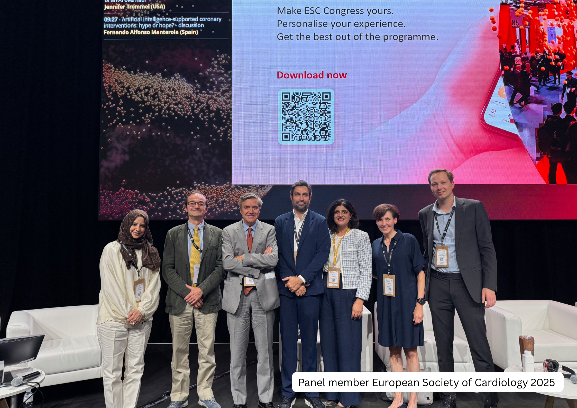 Seven individuals standing on stage at the European Society of Cardiology 2025 conference, with a large digital screen behind them displaying information about a conference event, including a QR code and text encouraging app downloads. The group incl