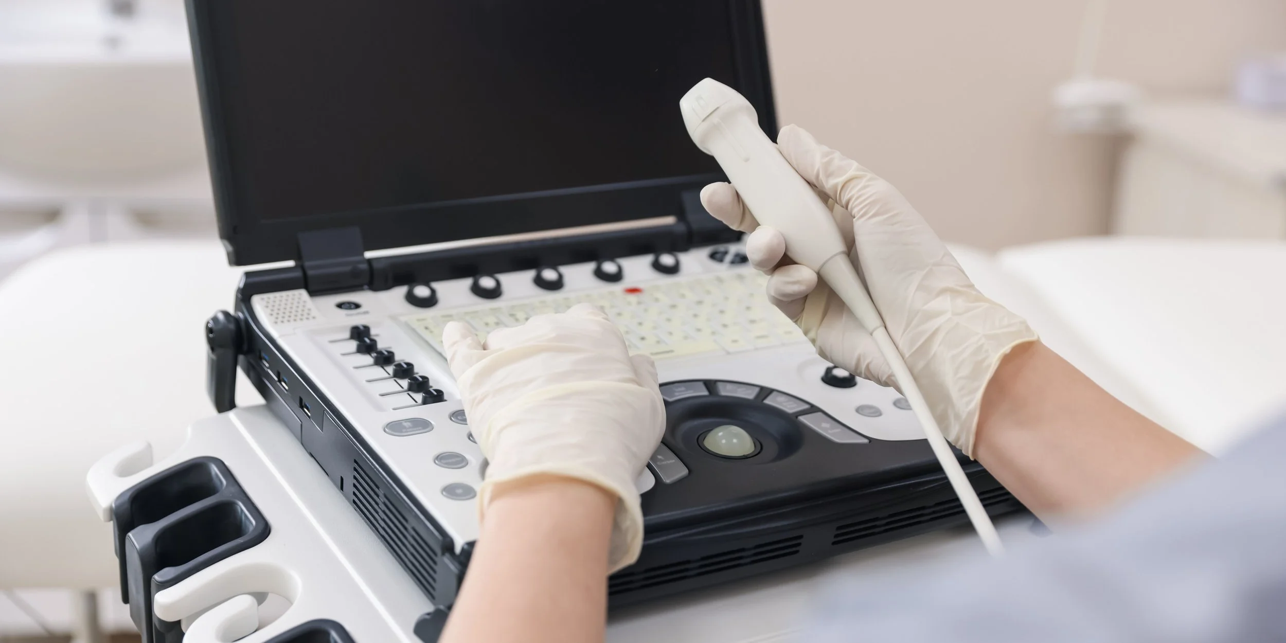 A medical professional wearing gloves using an ultrasound machine.