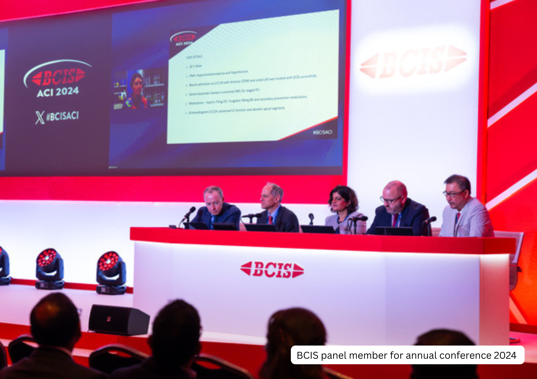 BCIS panel members sitting at a long table on a stage during the annual conference 2024, with large screens behind them displaying presentation slides and BCIS logos, and an audience in front.