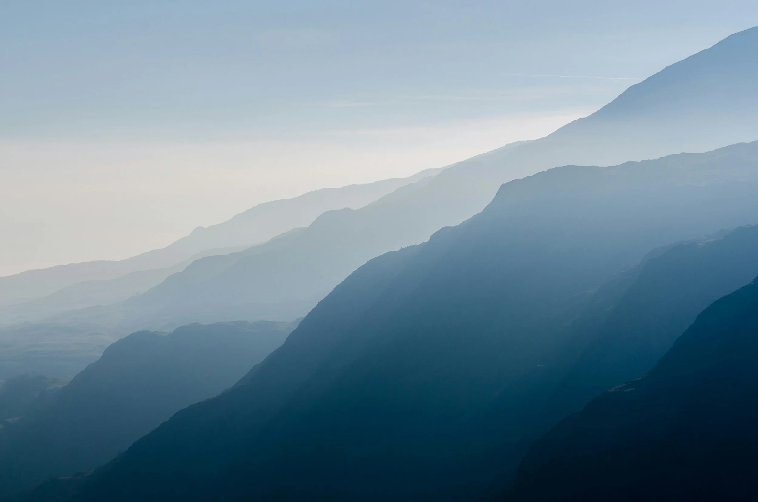 Layered mountain ranges fading into the distance under a clear light blue sky.