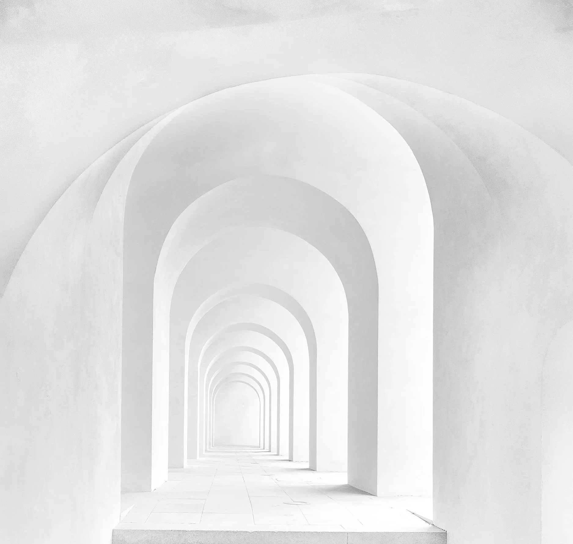 A series of white arches creating a tunnel effect, with the arches becoming smaller in the distance.