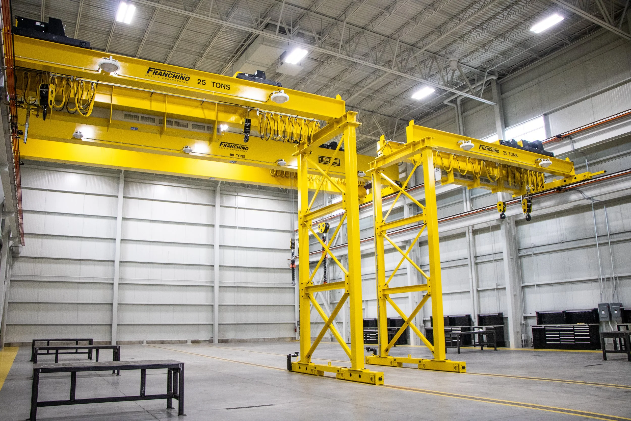 Industrial warehouse with two yellow overhead cranes labeled 'Franchino' and 'Wolf'.