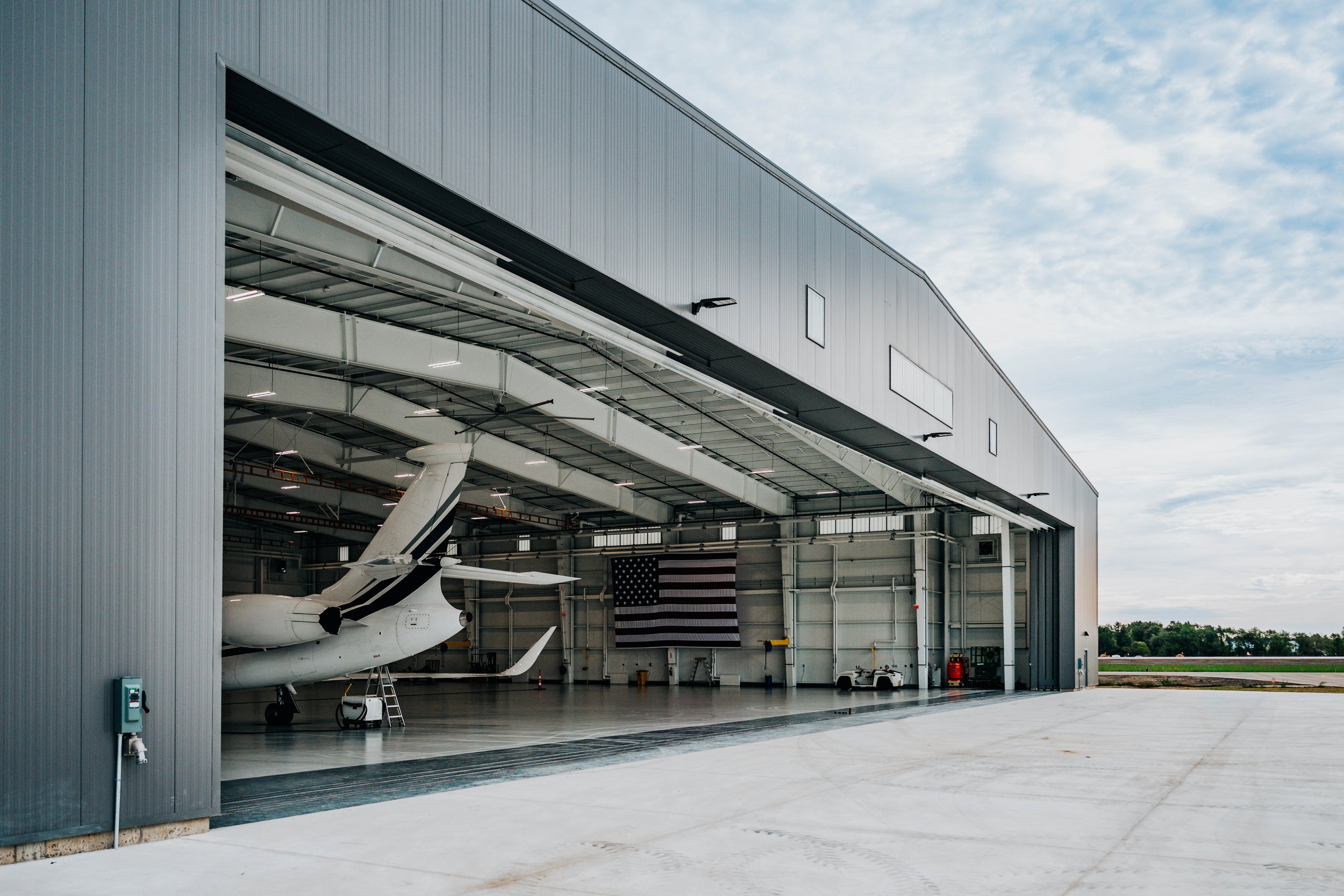 Angled view of the open hangar door at Stryker Sky High, with a corporate jet tail and interior steel framing