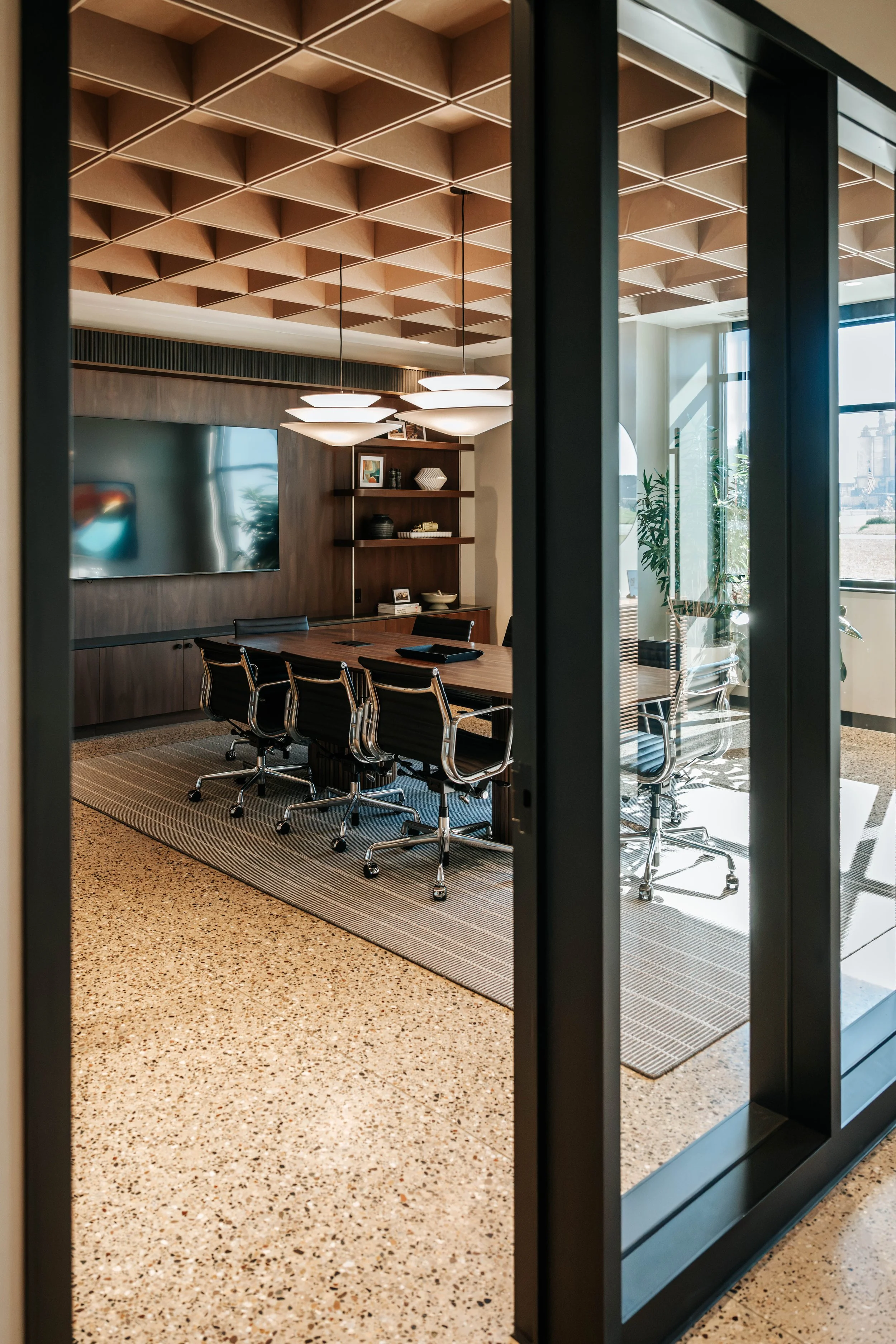 Conference room at PDM Properties seen through glass doors, with a wood coffered ceiling and a long conference table.