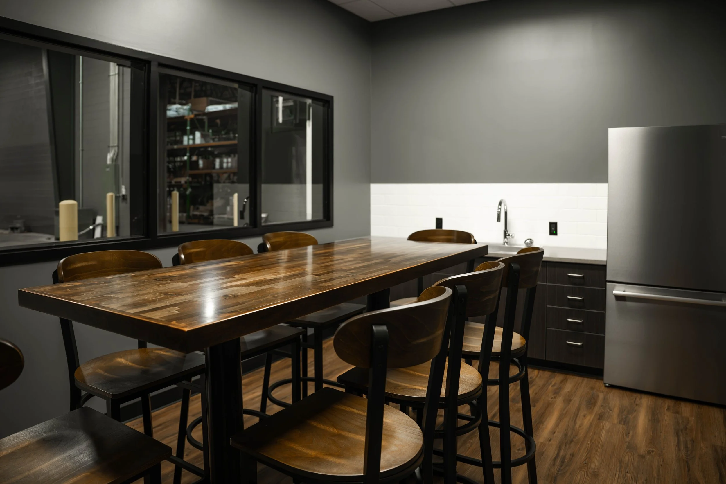 Employee breakroom with a high-top table and wood-look flooring in the Weller Auto addition