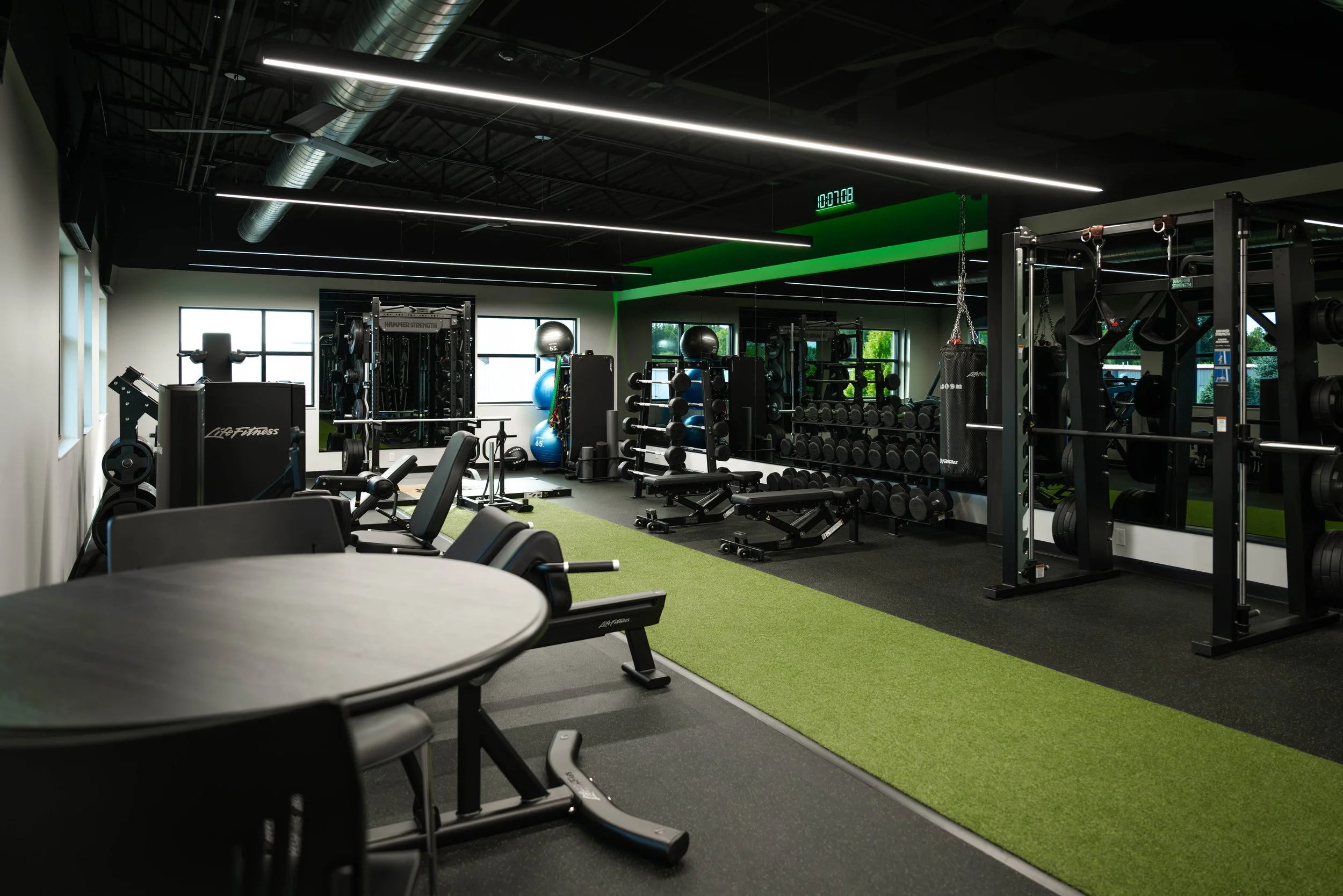 Employee gym at AFX with strength training equipment and a green turf lane.