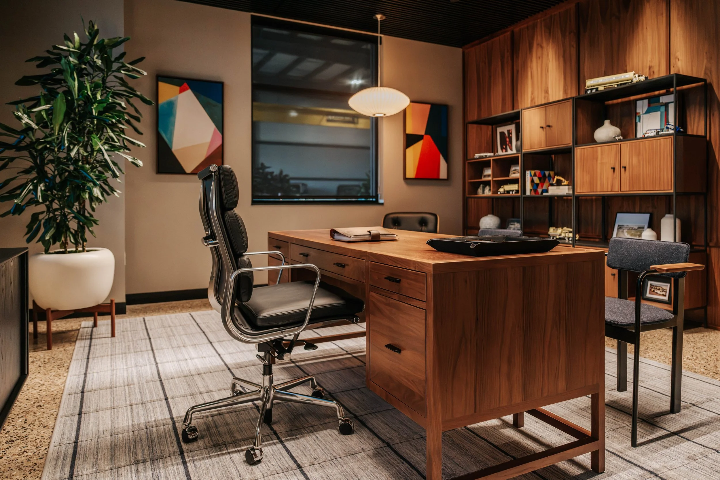 Private office at PDM Properties with a walnut desk, a leather desk chair and built-in shelving.
