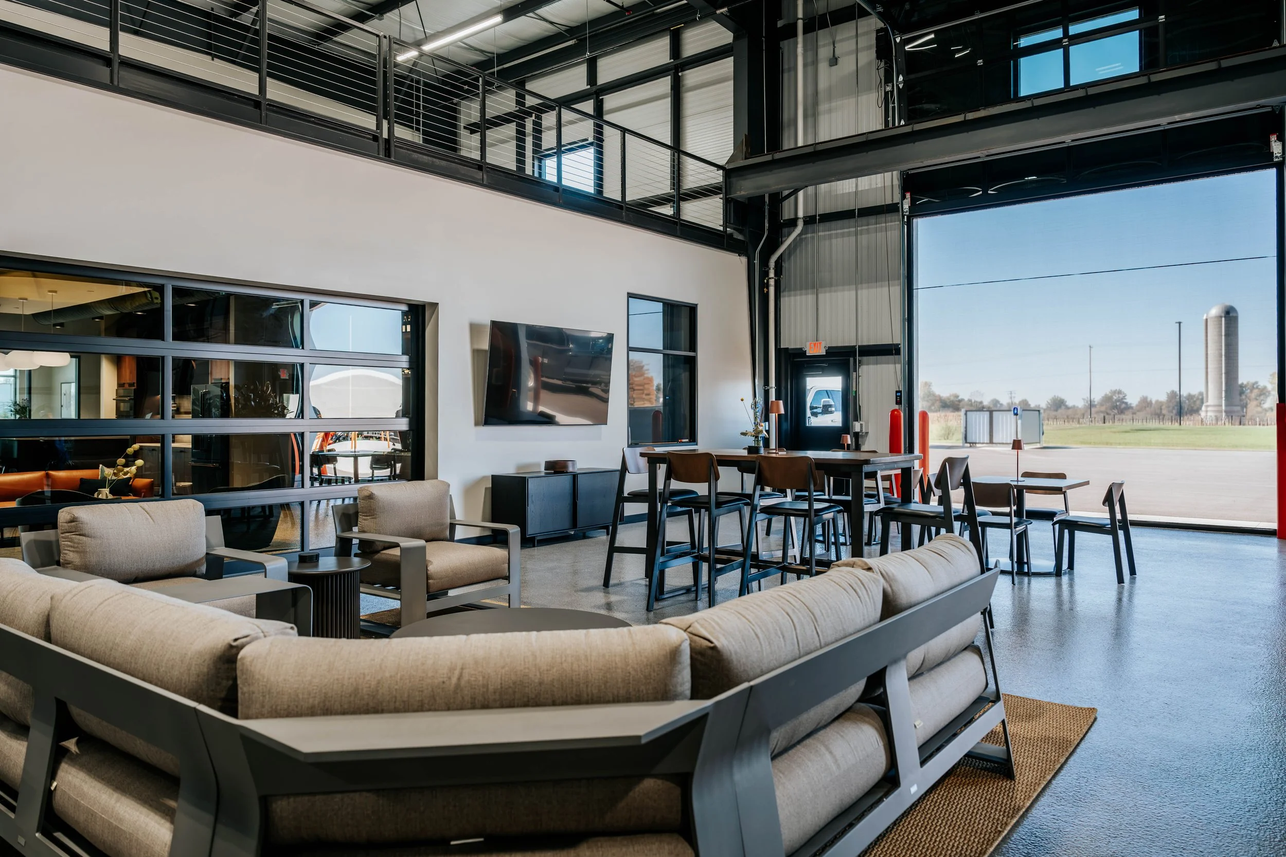 Lounge seating on the PDM Properties shop floor, with the mezzanine and an overhead door behind it.