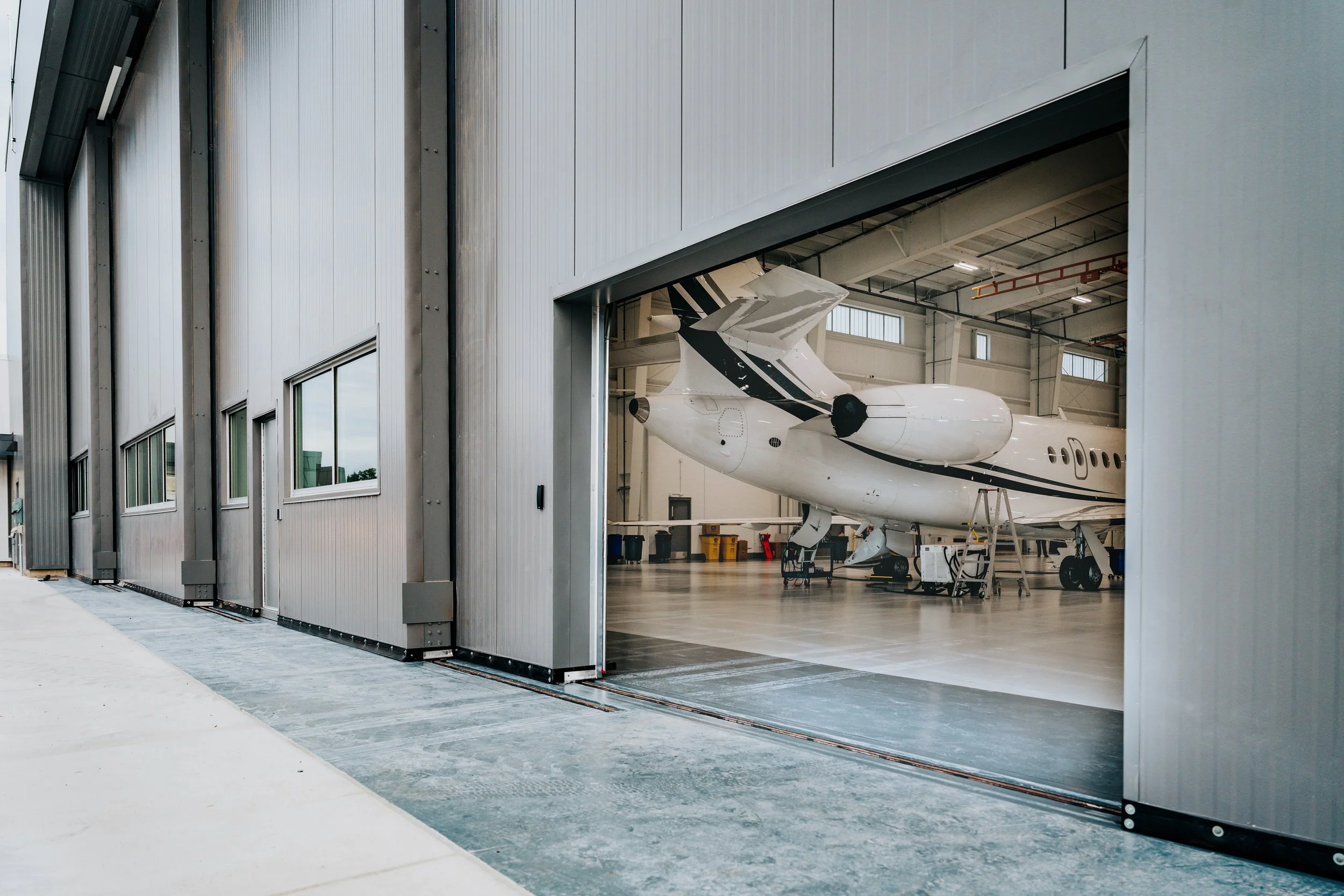 Close-up of the partially open hangar door at Stryker Sky High, with a corporate jet parked inside