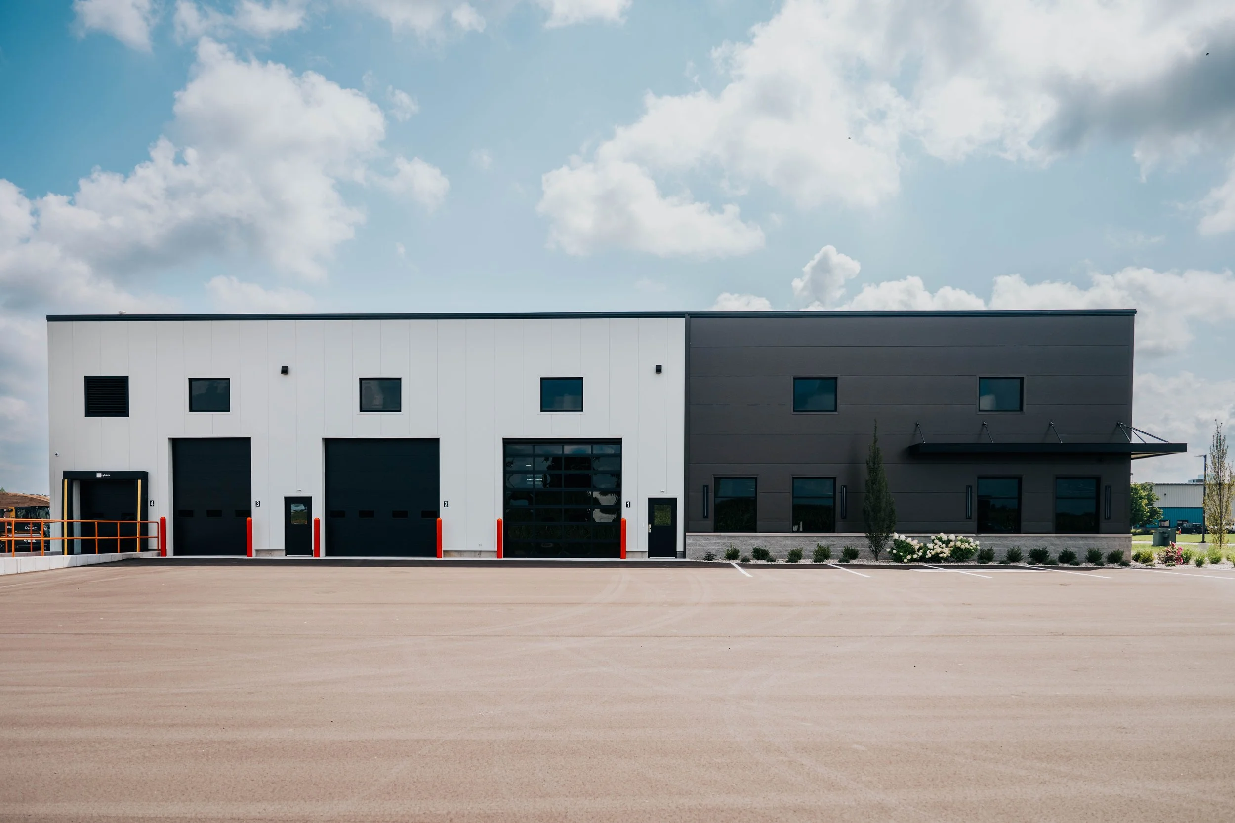 Exterior of the PDM Properties office and shop building in Dorr, MI, showing the overhead shop doors and the office wing.