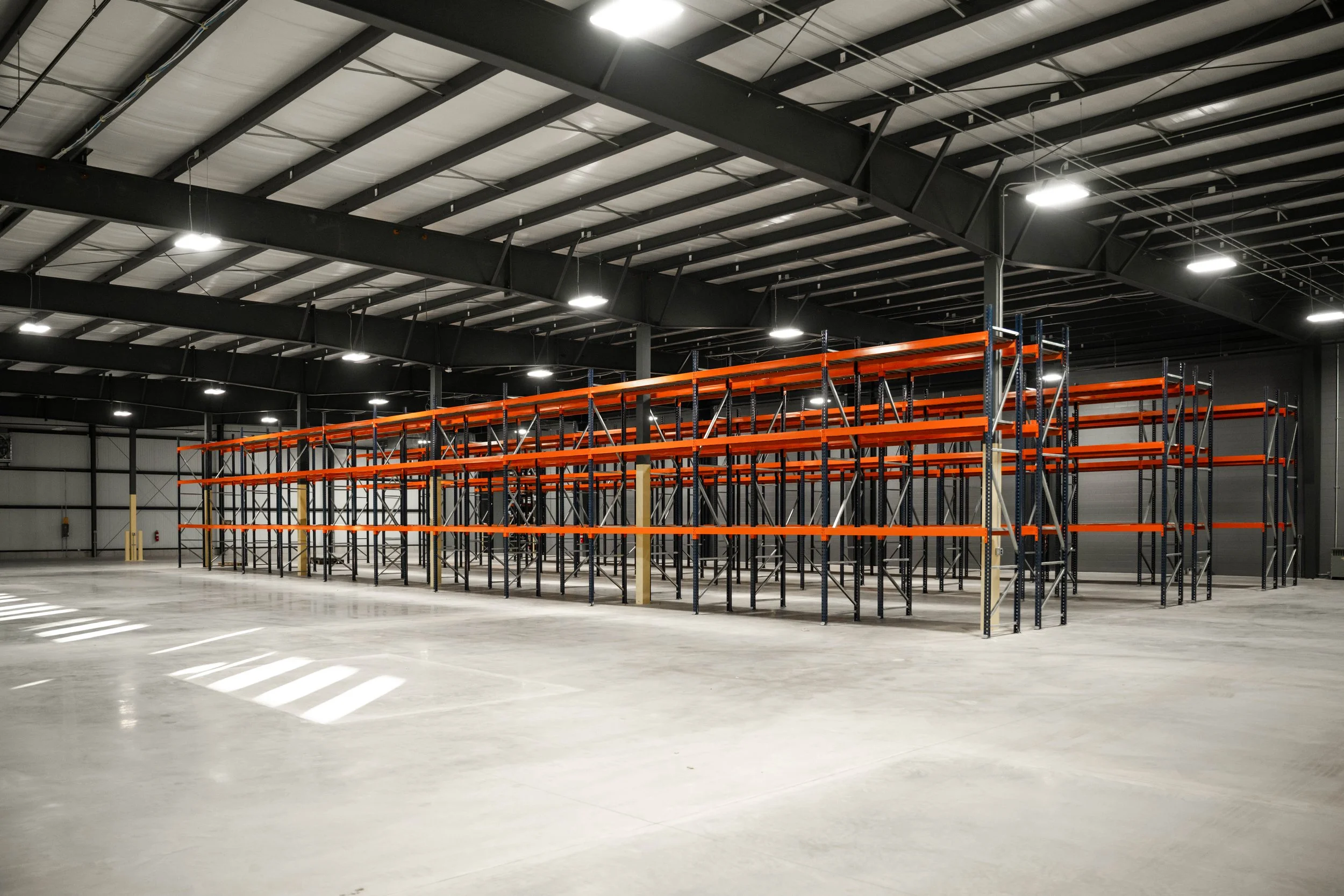 Open warehouse floor with pallet racking and high-bay lighting in the Weller Auto Parts addition