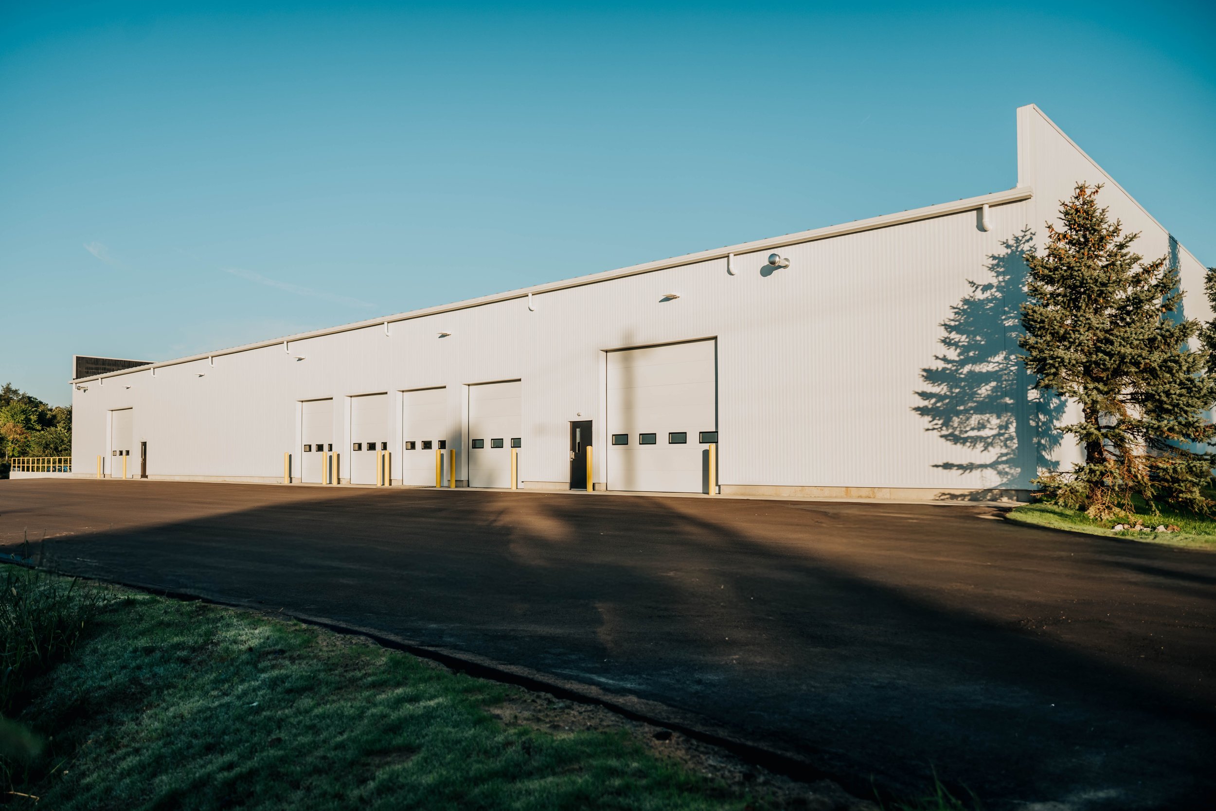 Exterior of the Weller Auto Parts pre-engineered metal building addition in Wyoming, MI, with overhead doors and new asphalt paving