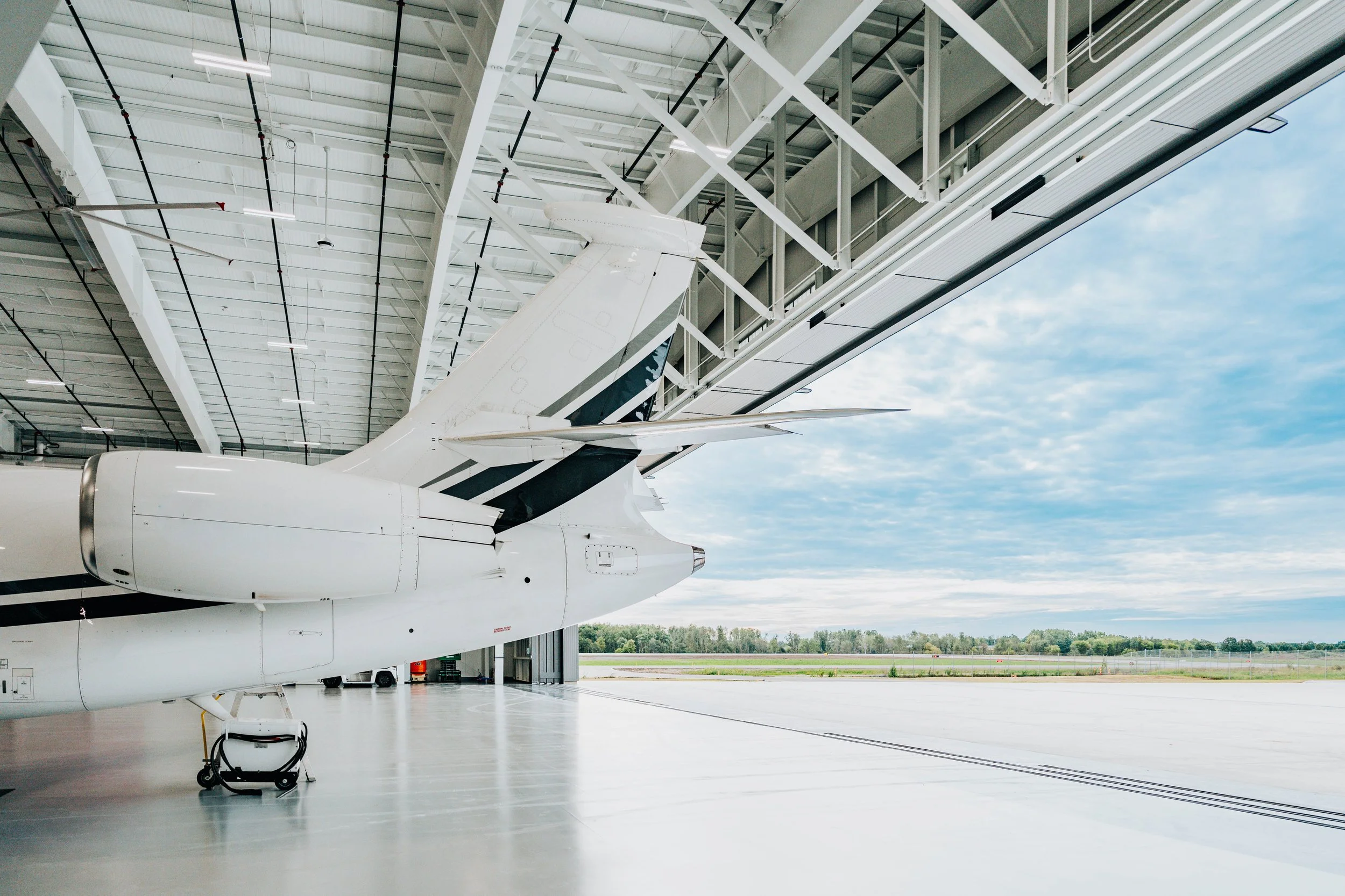 Corporate jet tail beneath the open hangar door header and steel framing at Stryker Sky High